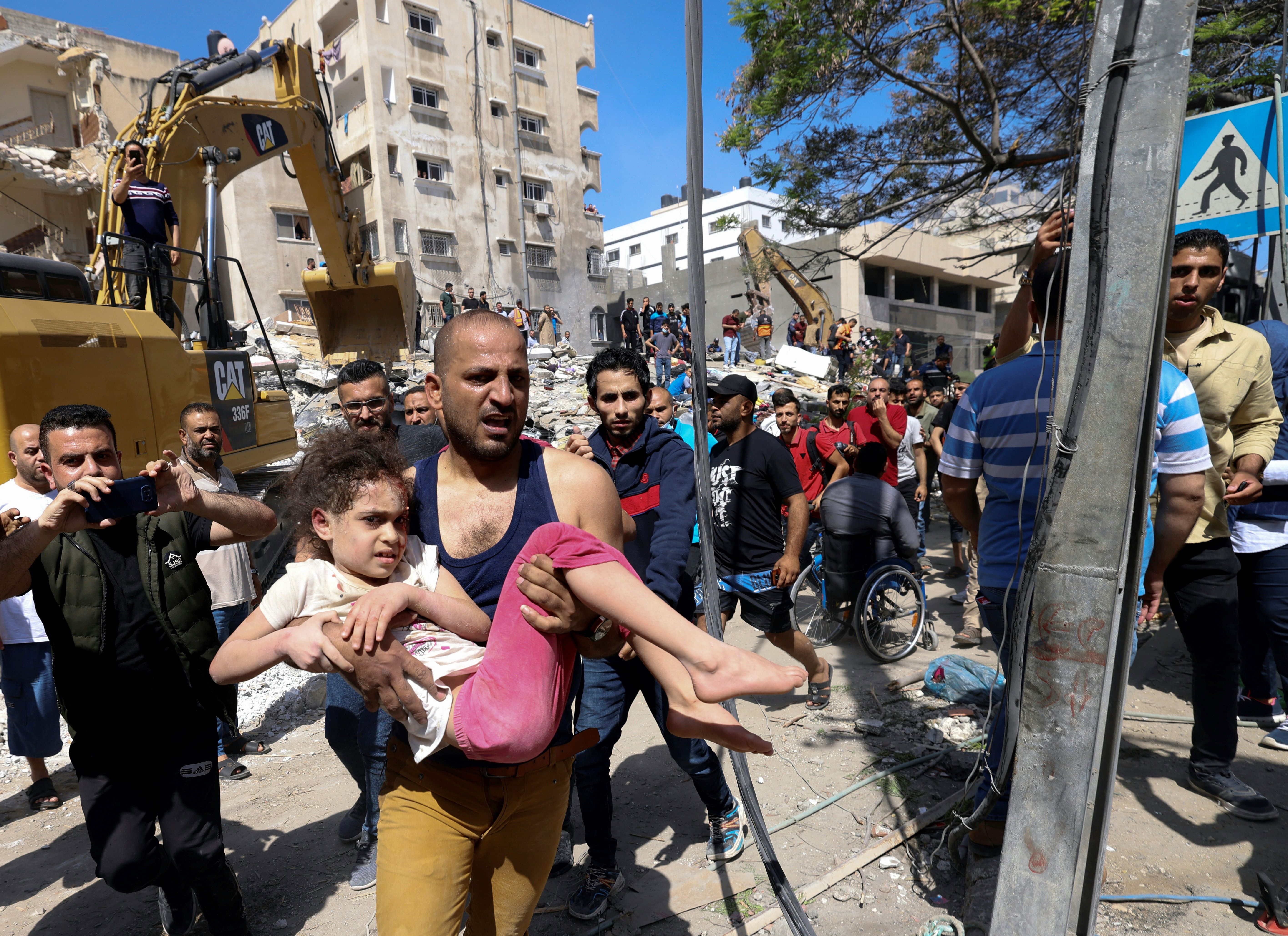Palestinians evacuate a wounded girl from the rubble of a destroyed building in Gaza City's Rimal residential district on May 16