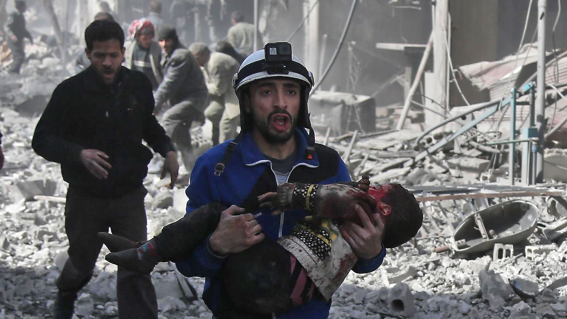 A Syrian civil defence member carries an injured child rescued following government bombing in the Eastern Ghouta region