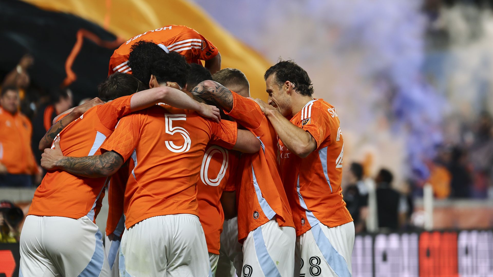 Dynamo players in orange jerseys celebrate after scoring a goal