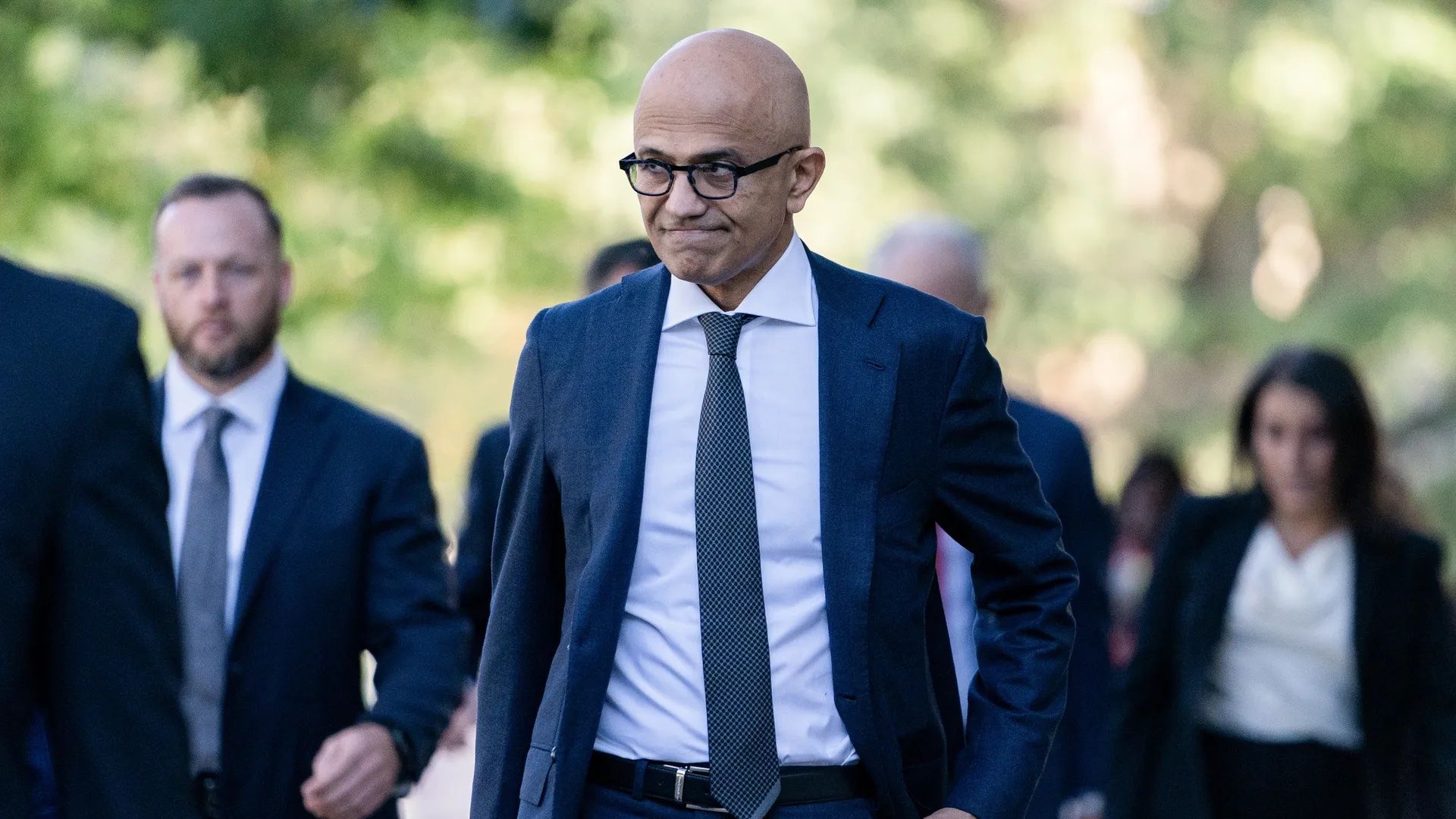 Photo of Satya Nadella in a tie and blazer walking