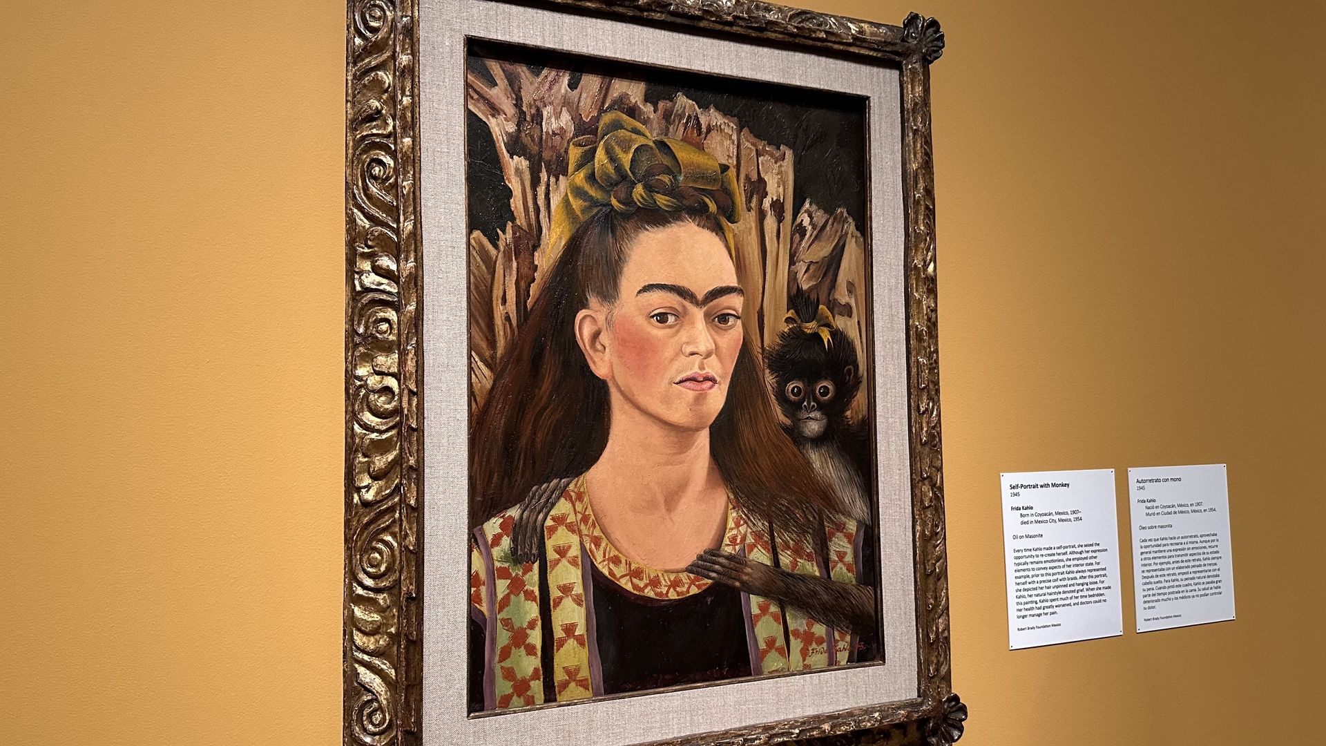 A framed painting of Frida Kahlo against a yellow wall