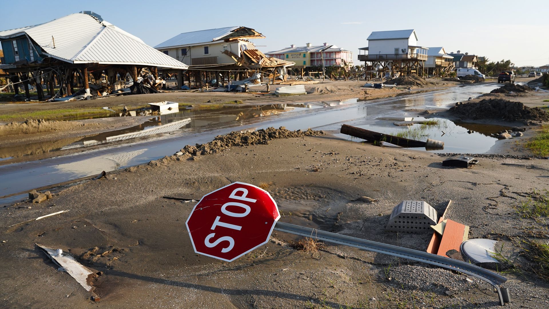 Bent stop sign with damaged homes in the background following Hurricane Ida's landfall in Louisiana.