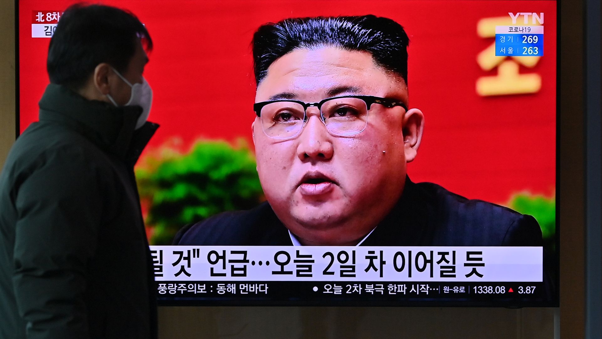 A person watching news footage of North Korean leader news footage of Kim Jong Un speaking in Pyongyang in January 2021.