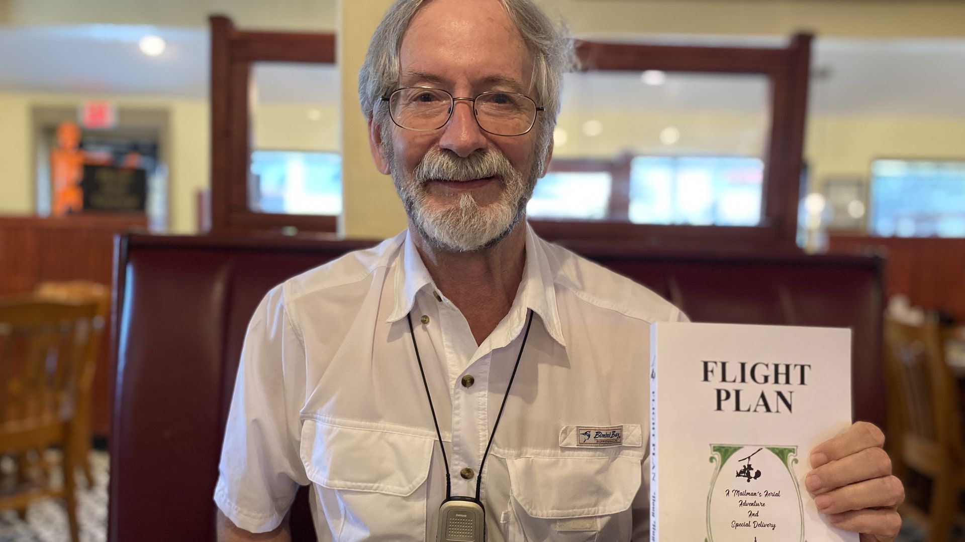 Doug Hughes holding his book up in a cafe. 