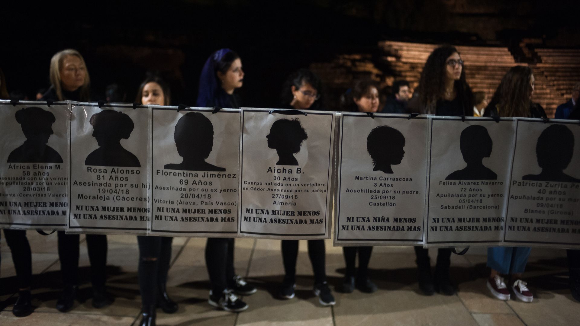 Women hold up signs with the names of women who were killed in Spain by their partners this year. 