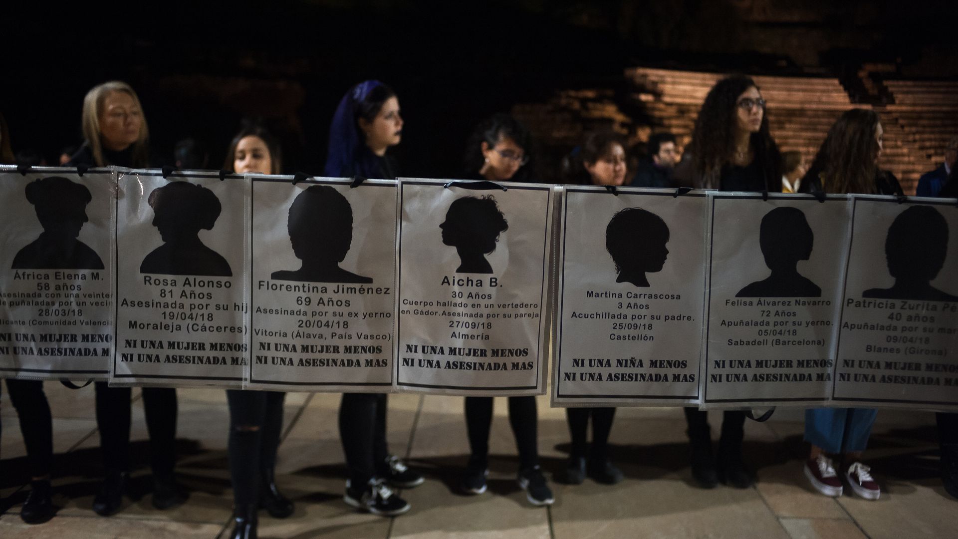 Women hold up signs with the names of women who were killed in Spain by their partners this year.