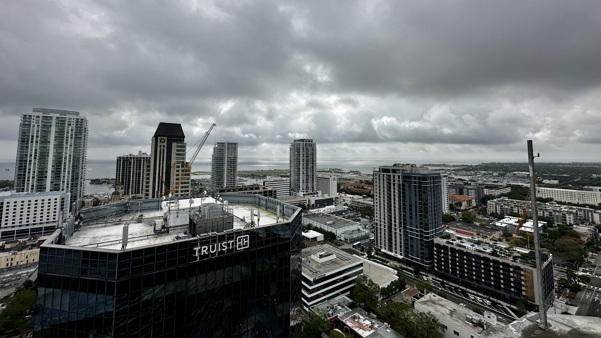 A city skyline of 4-5 skyscrapers with the backdrop of a gray cloudy sky.