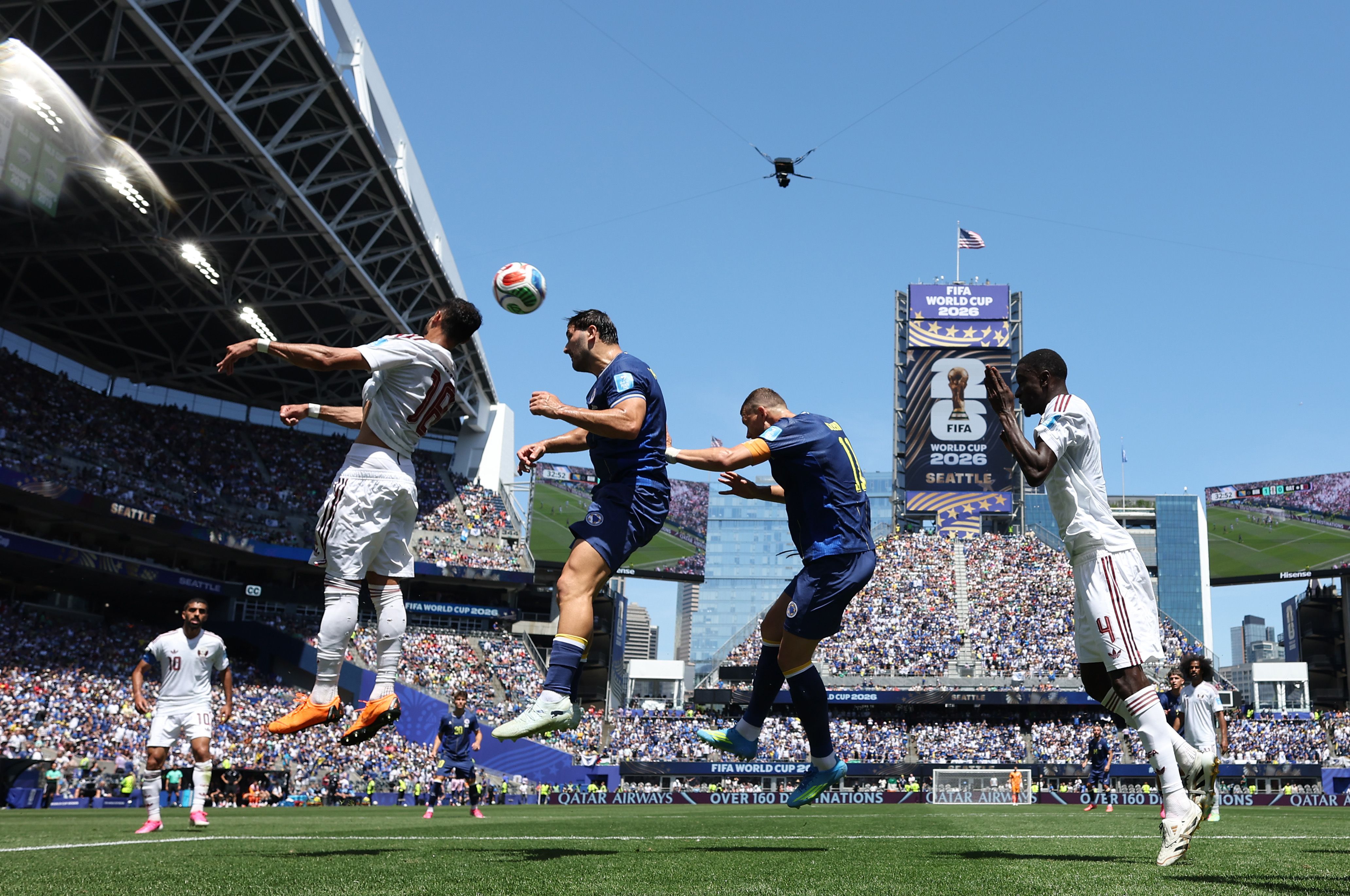 Sultan Albrake #18 of Qatar competes for a header against Sead Kolasinac #5 and Edin Dzeko #11 of Bosnia and Herzegovina during the FIFA World Cup 2026 Group B match between Bosnia and Herz
