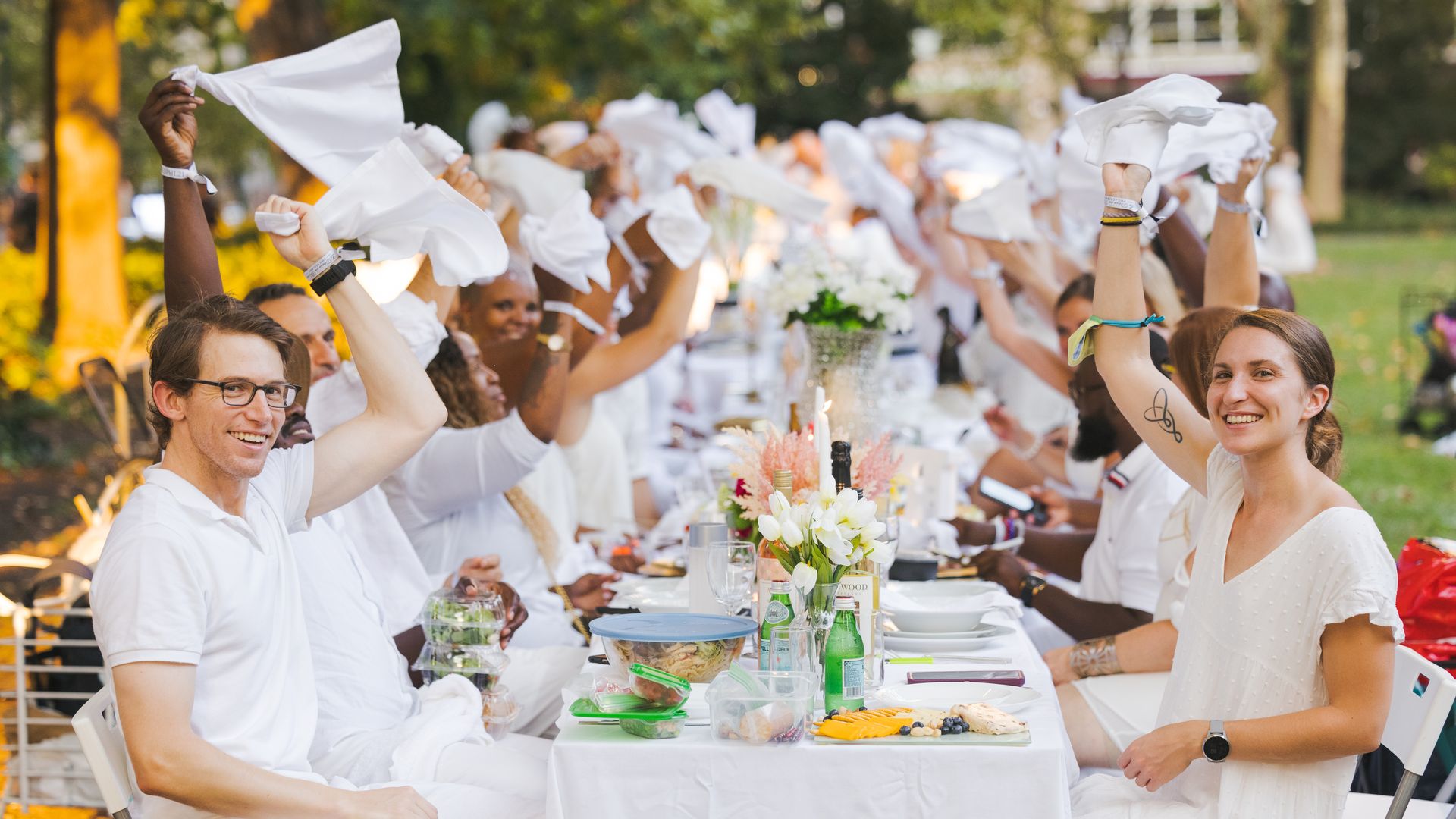 Seated diners wave their napkins during a Dîner en Blanc Philadelphia event.