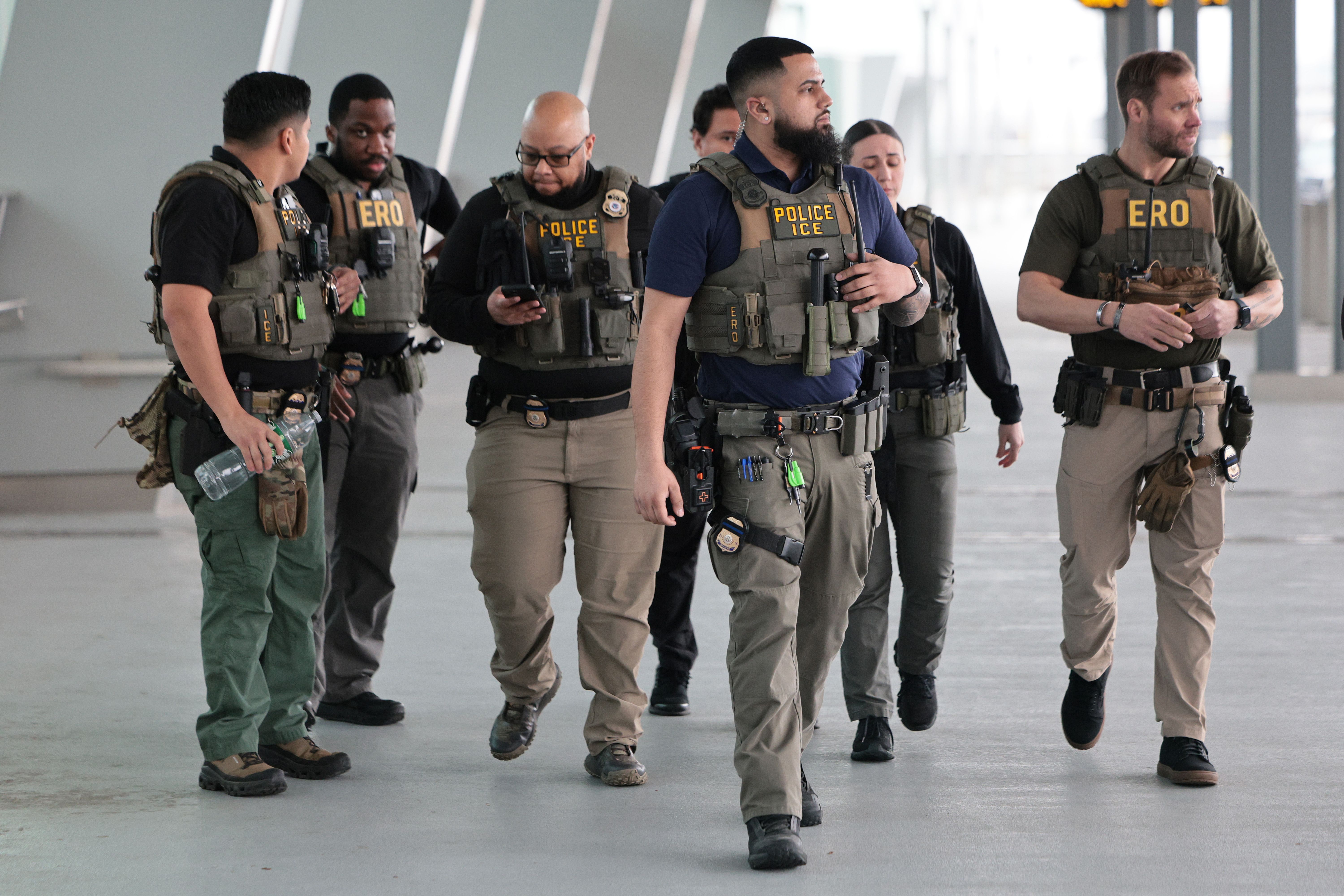 ICE agents walk through a terminal at LaGuardia Airport while travelers move through security during disruptions.