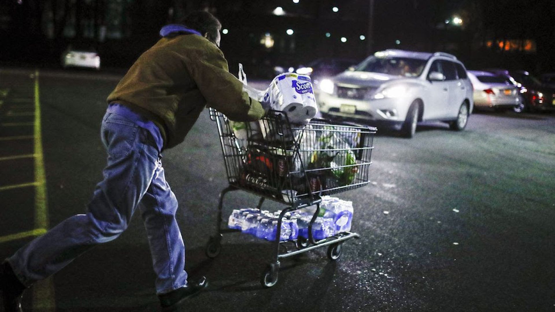 Man pushes a grocery cart in a parking lot