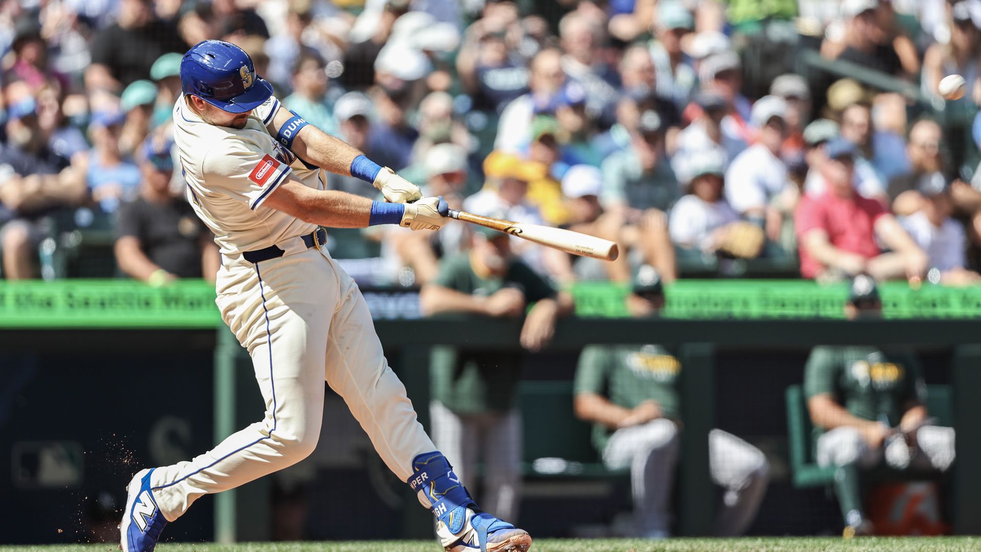 A baseball player in white and blue swings the bat for a hit that will become a homer.