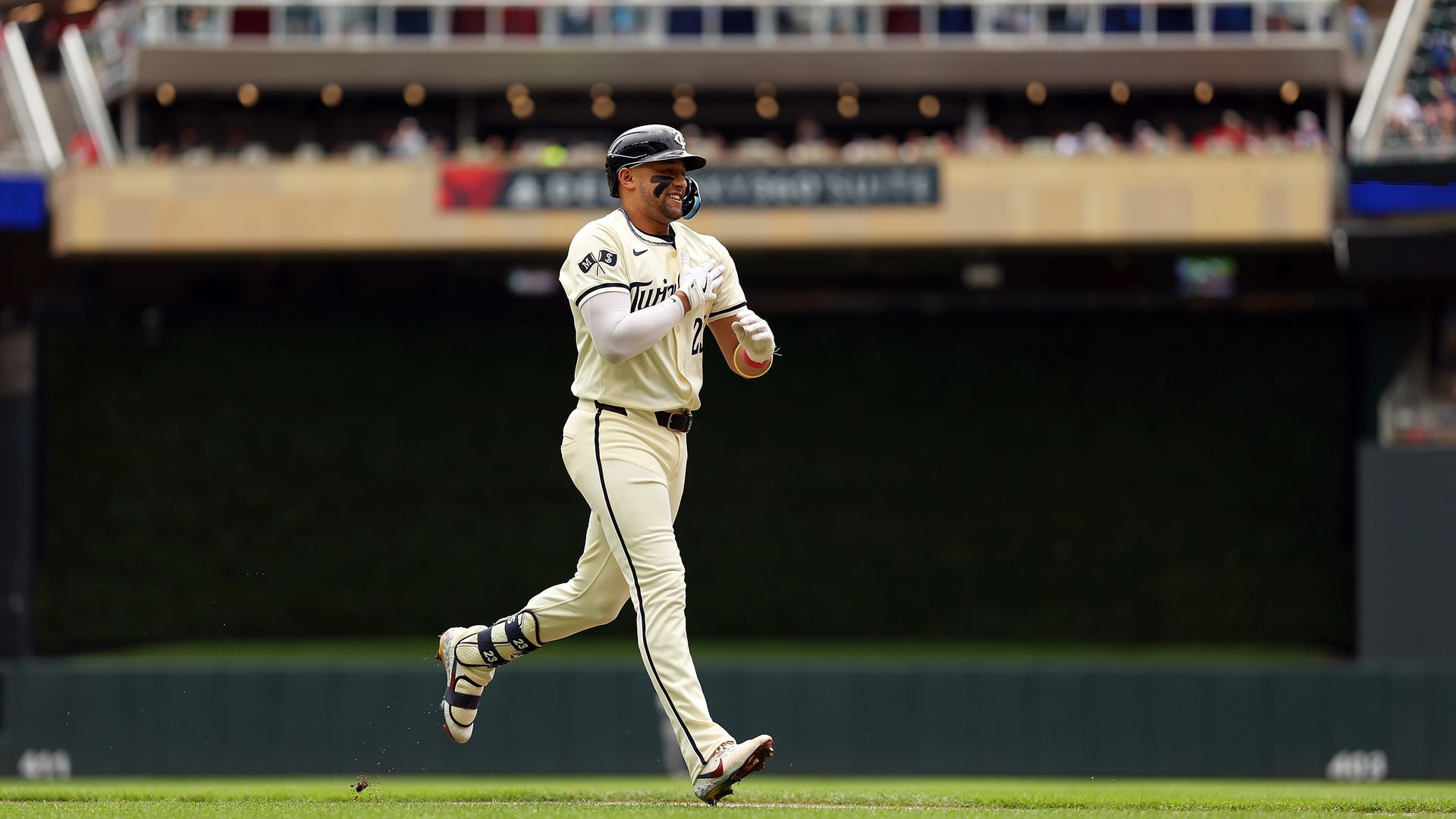 baseball player Royce Lewis running in a white uniform with a helmet