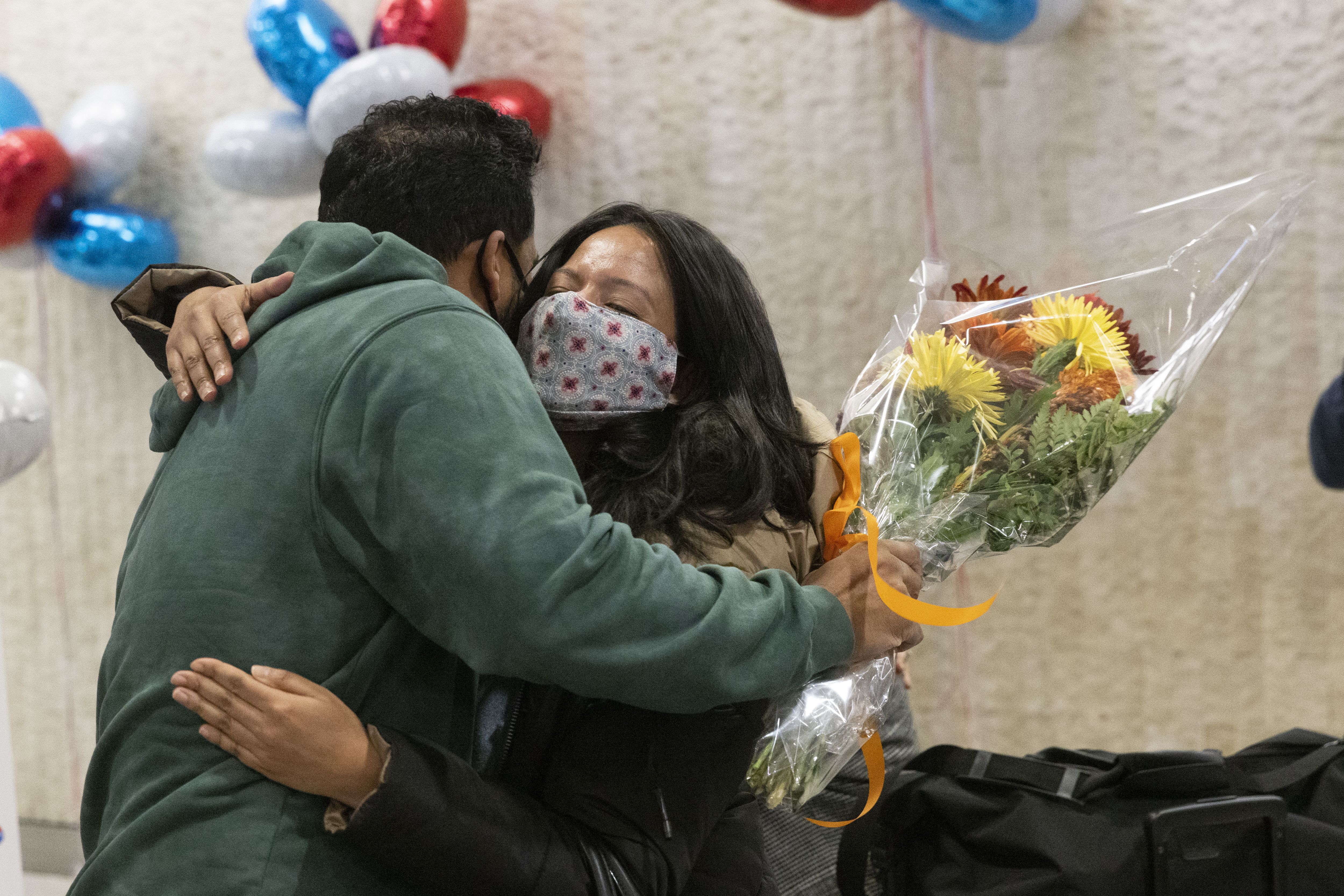 A man and woman hug at JFK arrivals area