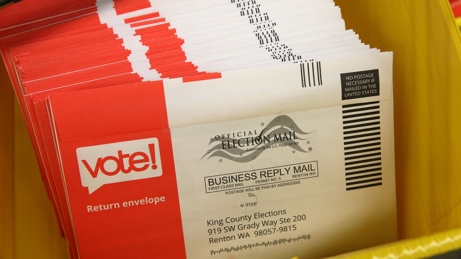 A pile of ballots in red and white envelopes waiting to be sorted, with the word "vote" written on one side.