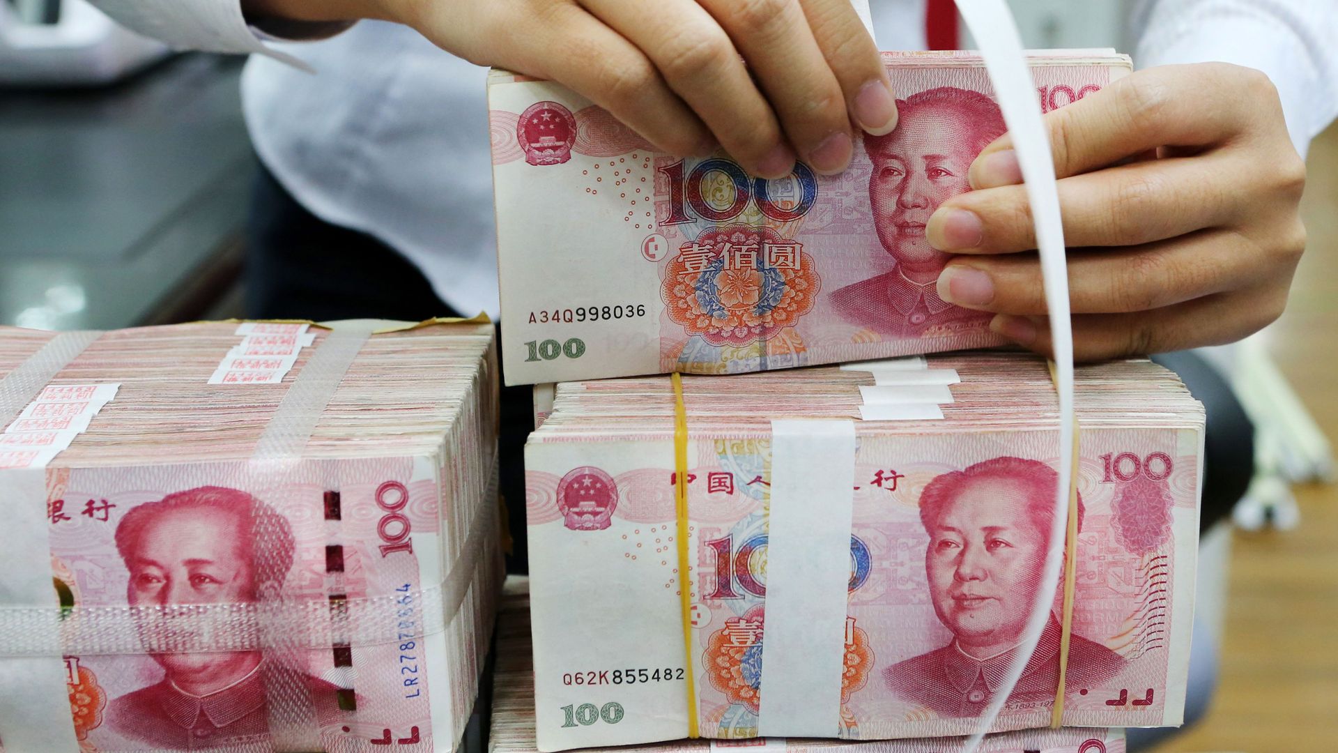 A woman ties a ribbon around a stack of yuan