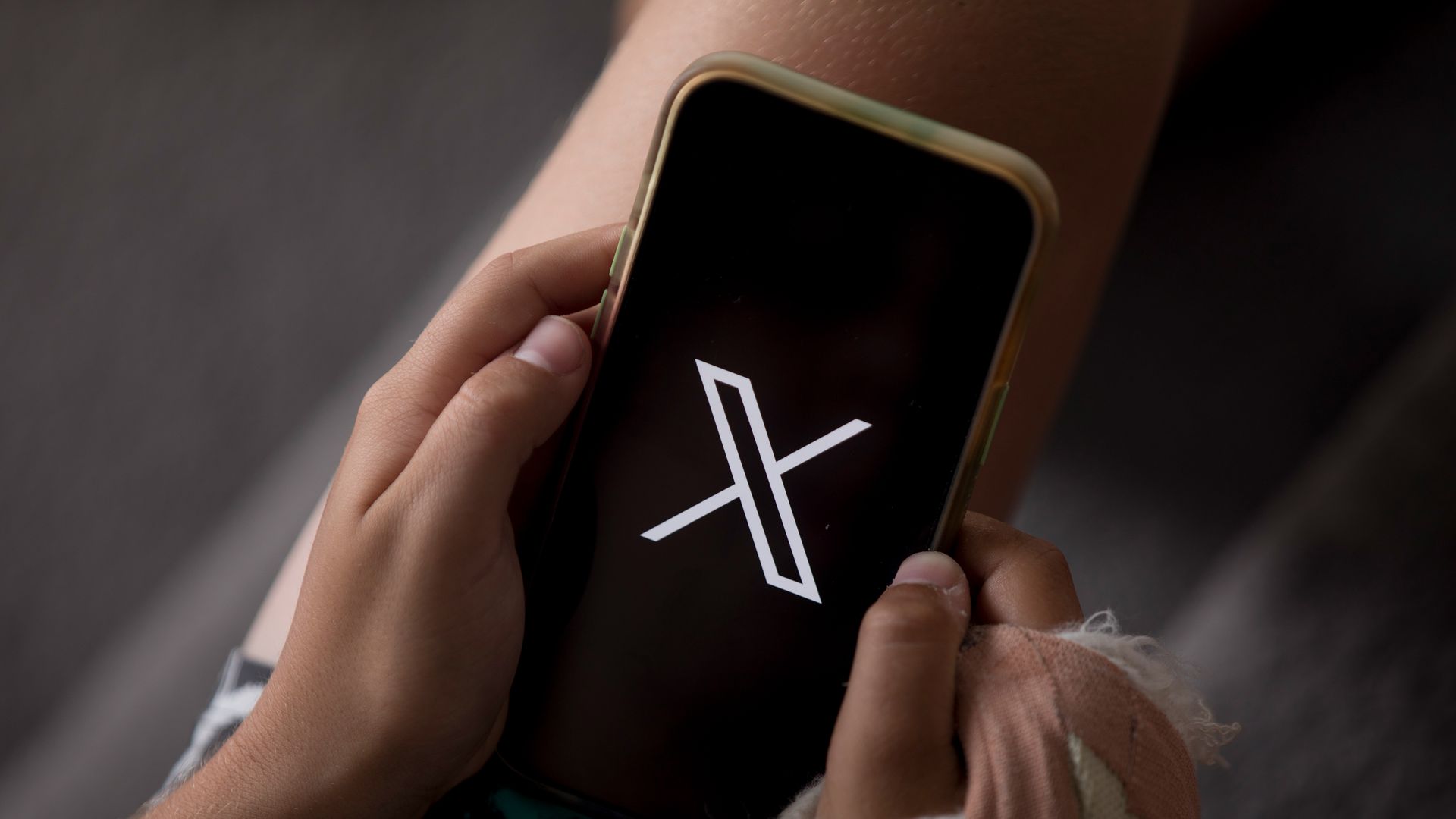 Two hands hold phone with X logo
