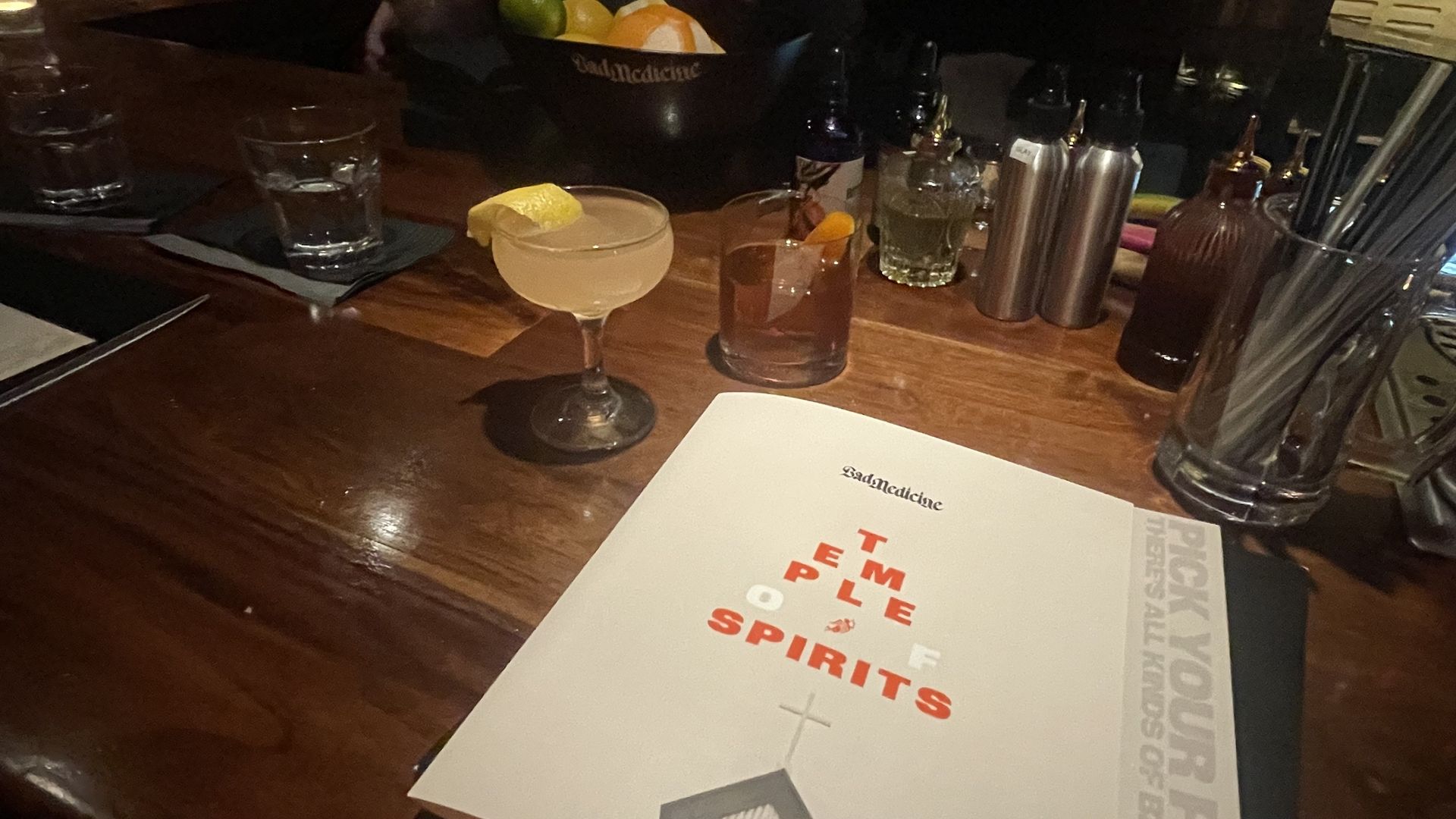 A bar with two cocktails on it and a menu