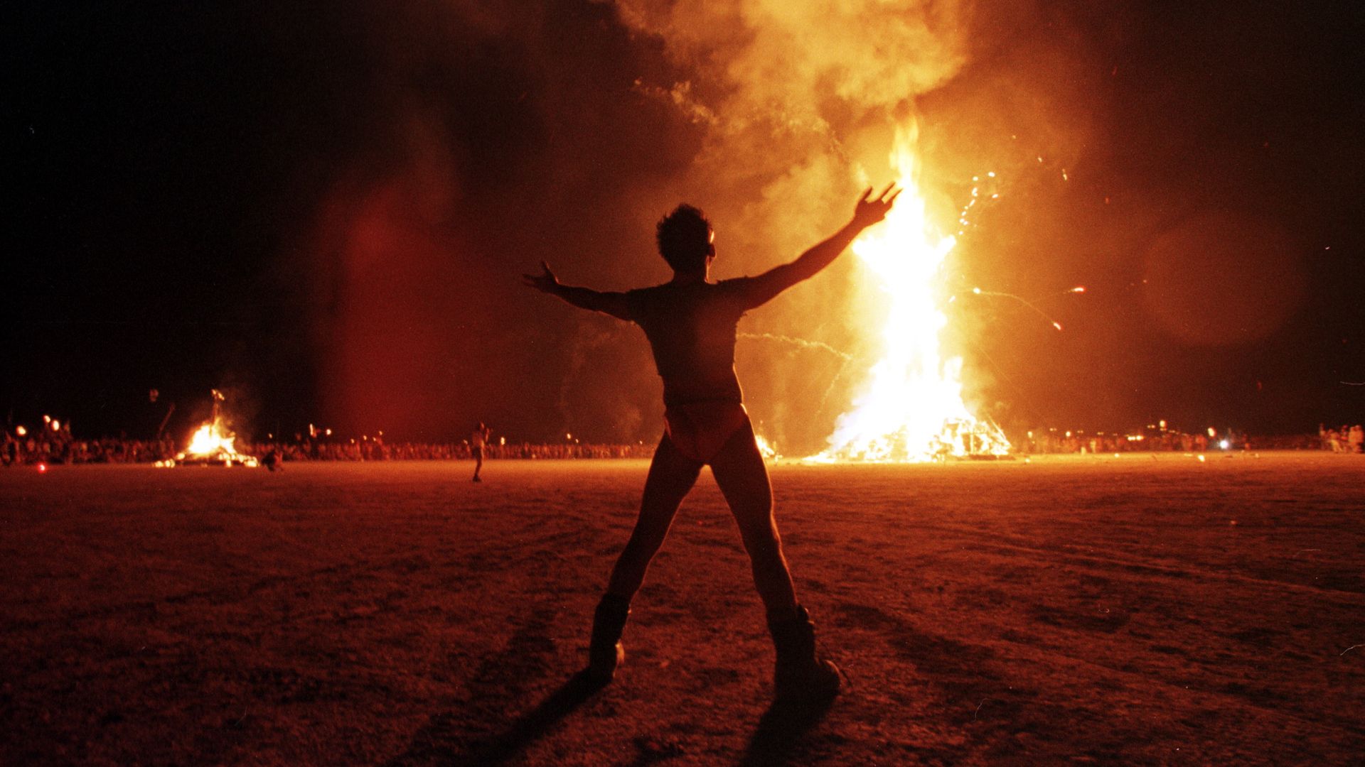 A "Burning Man" participant holds up his arms as the wooden man effigy is burned at the conclusion of the week-long "Burning Man Festival"