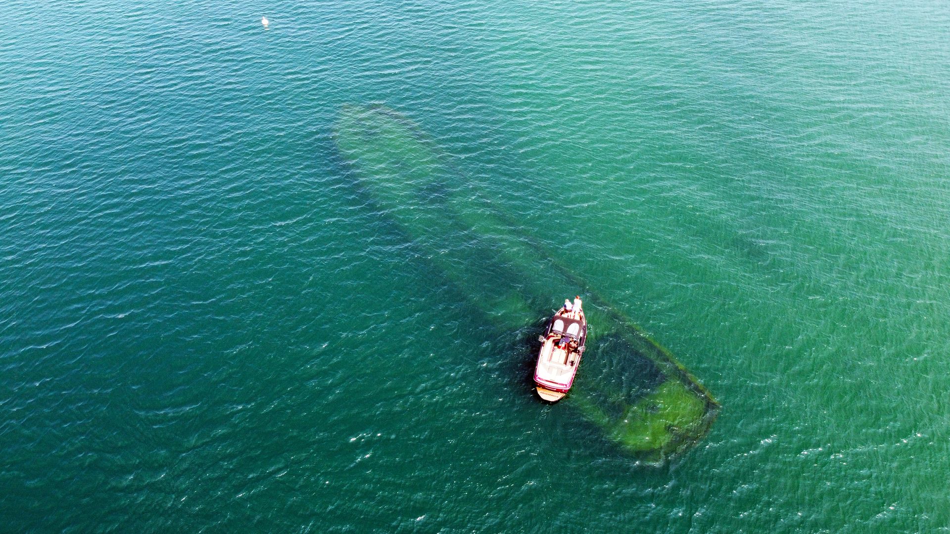 A boat on Lake Superior floating atop a submerged shipwreck.