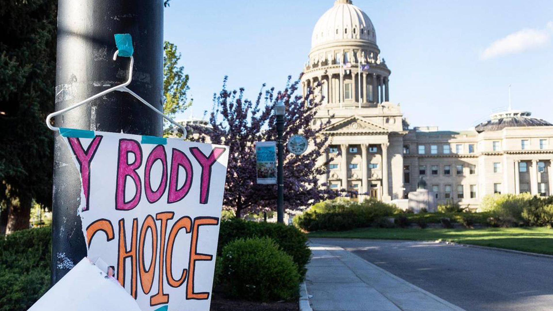 Picture of a ripped sign that says "my body my choice" taped on a pole in front of the Idaho state Capitol