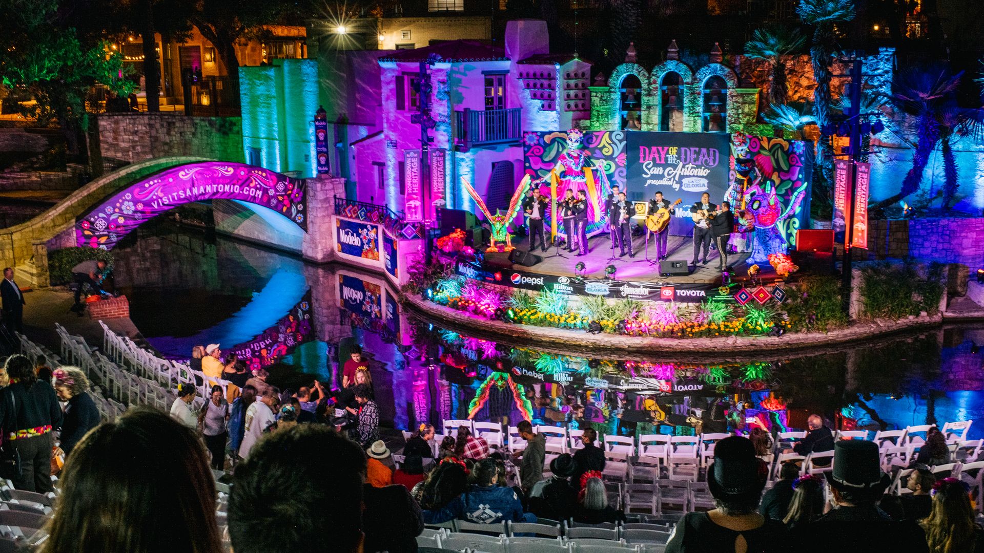 A view of a river theater decorated with bright colors and lights as mariachis perform.