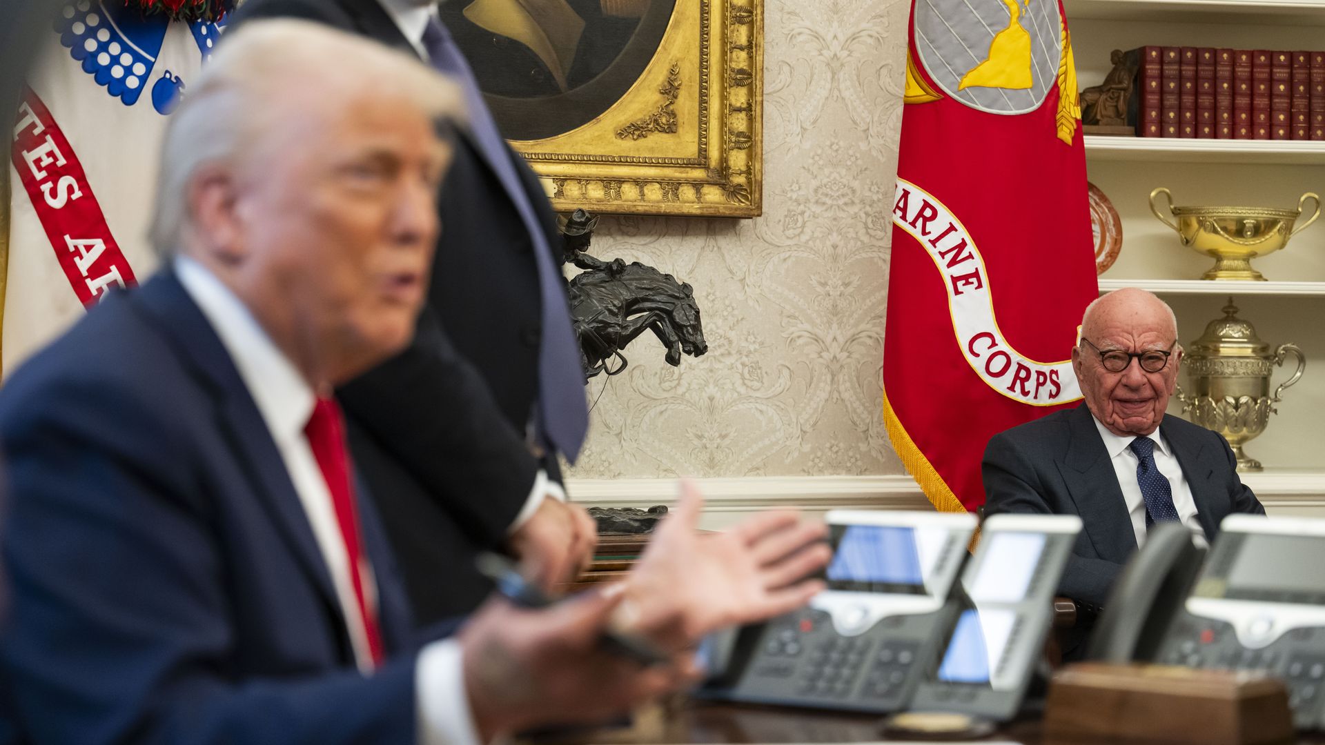 President Trump seated in the Oval Office, with Rupert Murdoch looking on from a chair to the side.