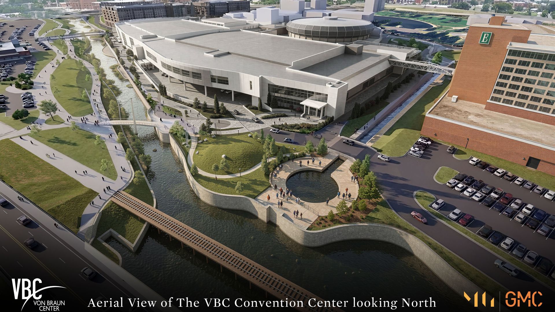 An aerial view of the VBC Convention Center: modern complex with circular glass dome, canal, bridges, green spaces, and distant skyline, looking north.
