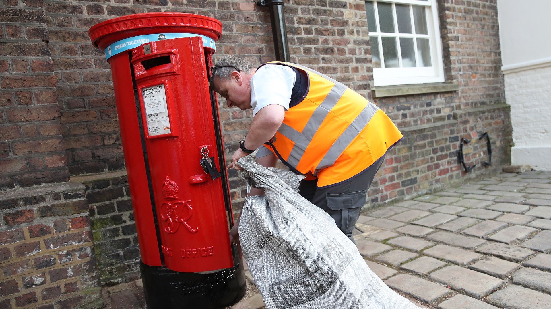 Photo of a postal worker emptying a postbox