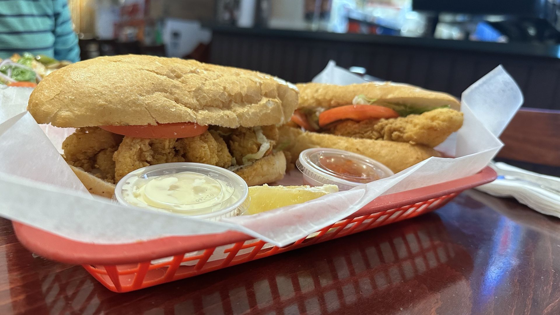 Photo shows a poboy in a red plastic serving basket.