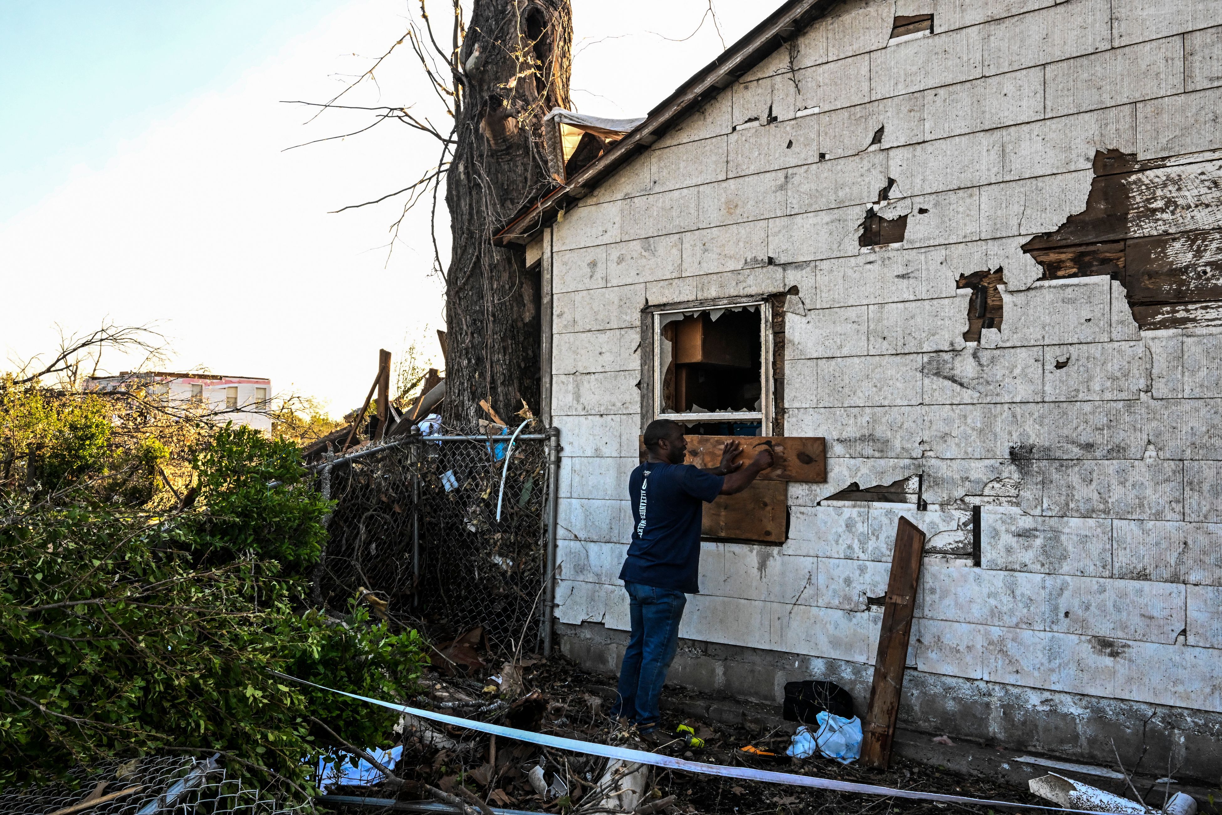 A man repairs a window on his home in Rolling Fork, Mississippi after storms and a tornado.