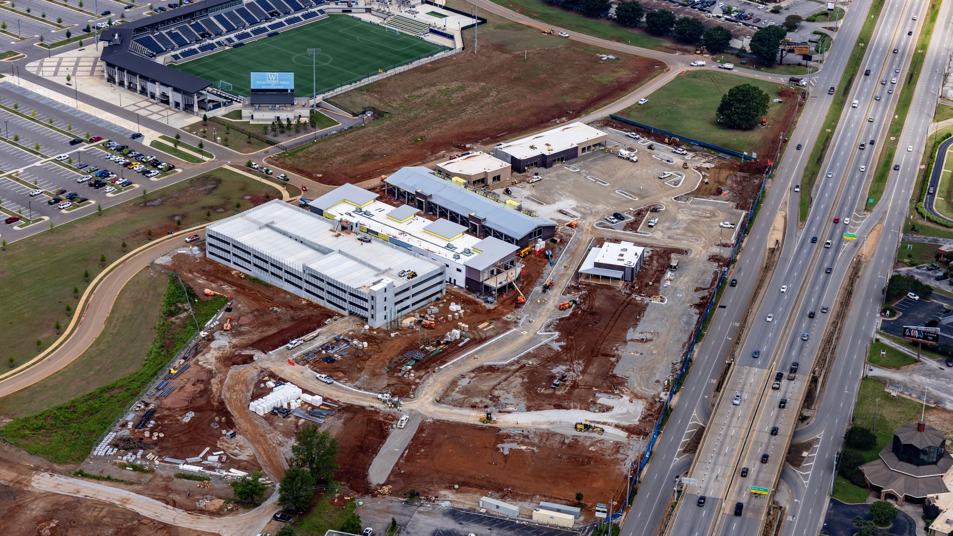 an aerial photo of an under-construction mixed use development near a soccer stadium