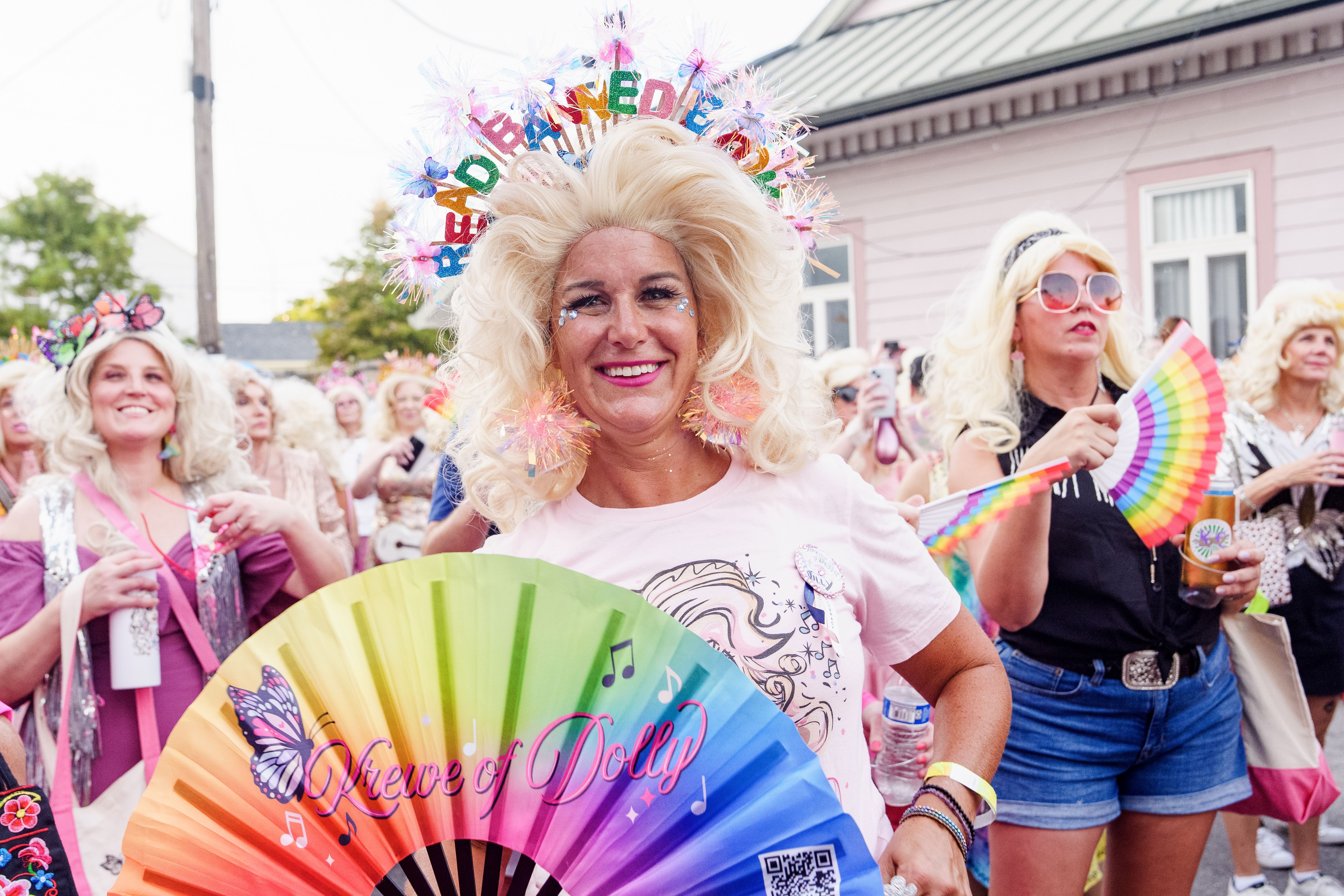 Image shows a woman dressed as Dolly Parton. She's marching with the Krewe of Dolly in a parade.