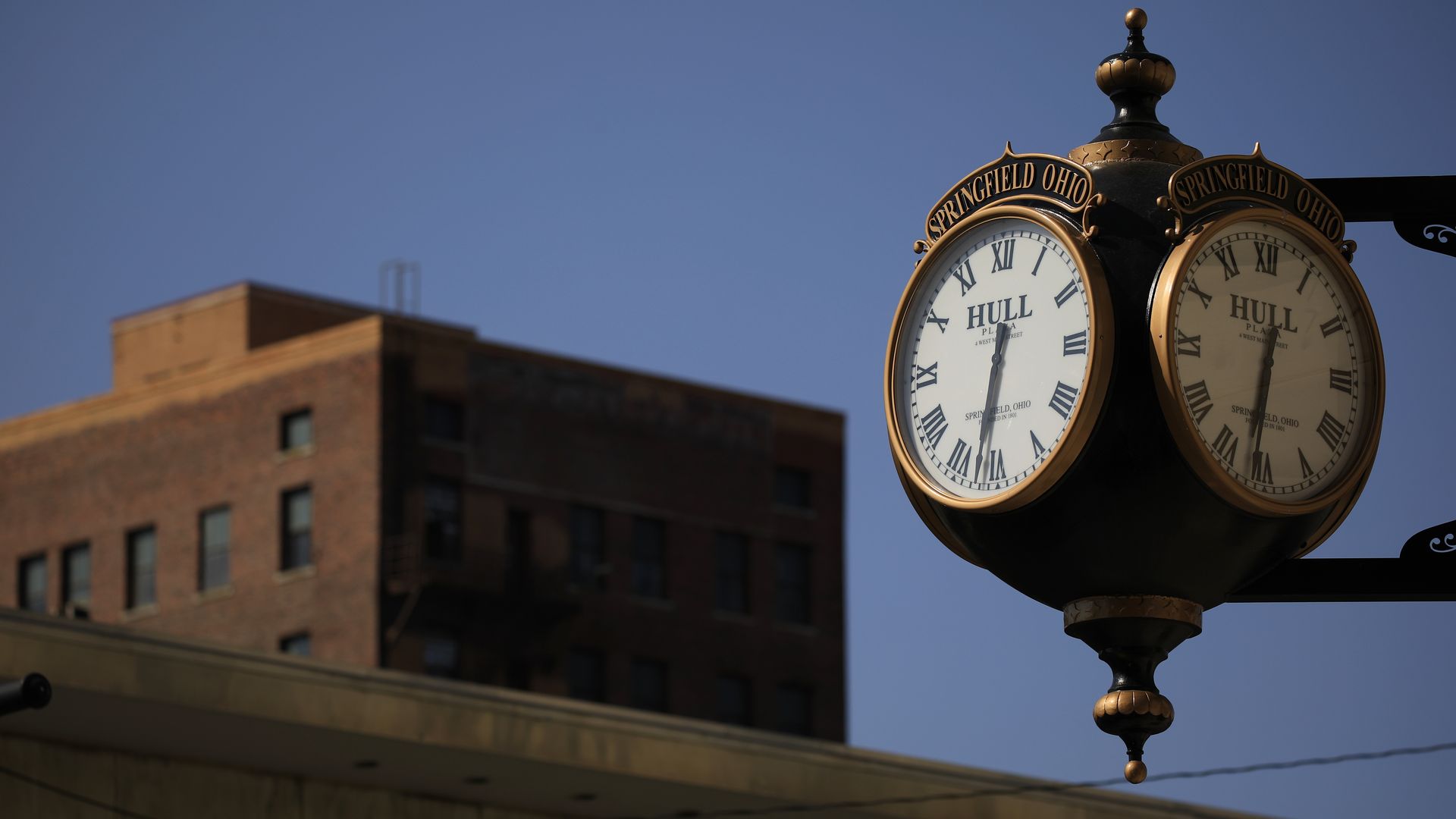 An antique clock hanging off a building in downtown Springfield with the words "Springfield, Ohio" inscribed. 