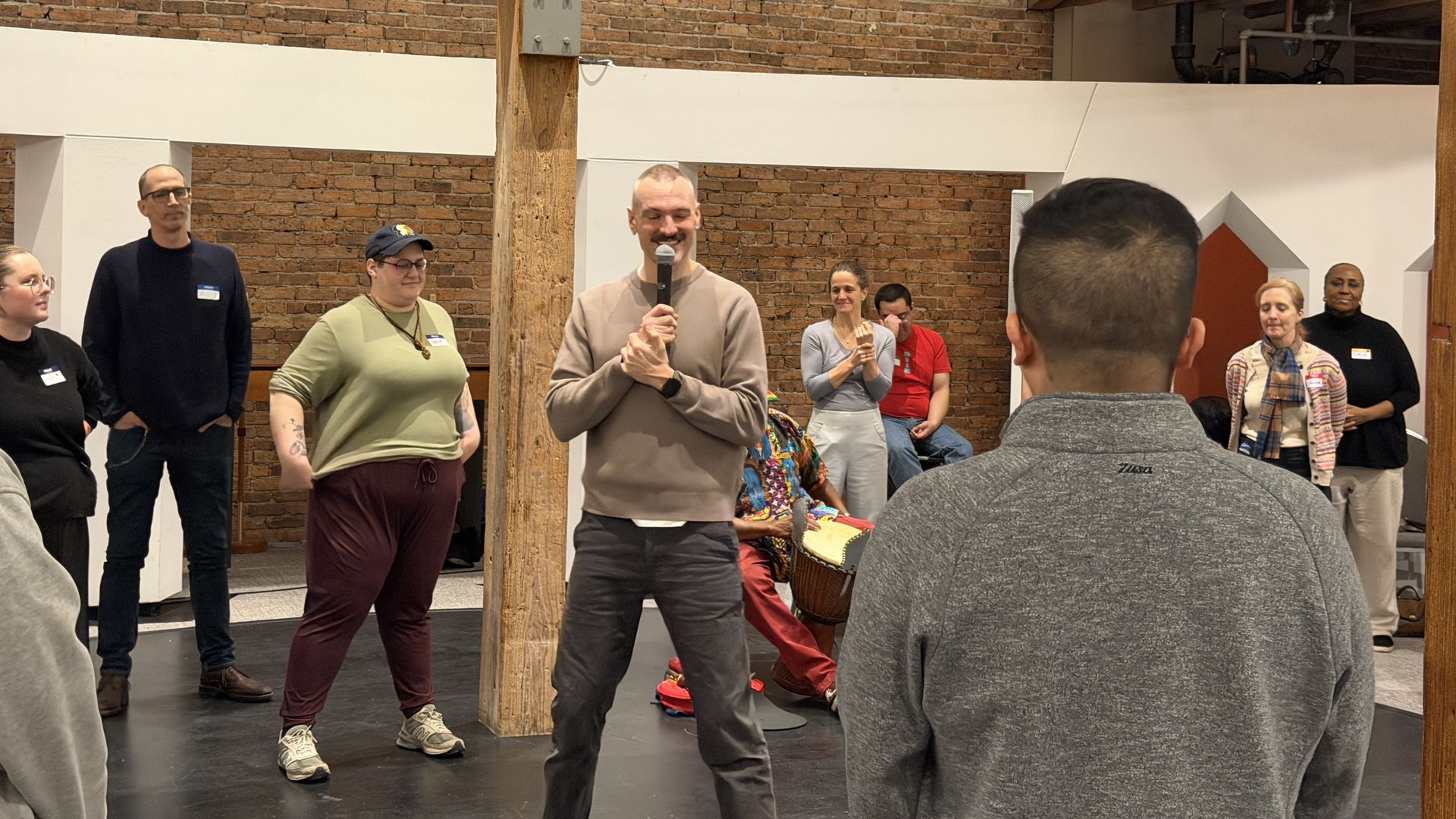 guy with a microphone stands in the middle of a group of people 