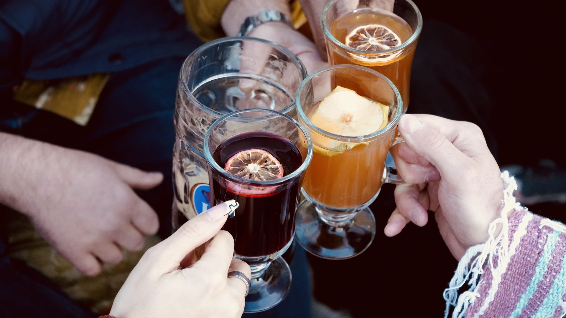 A group of people cheers with mulled wine and hot cider