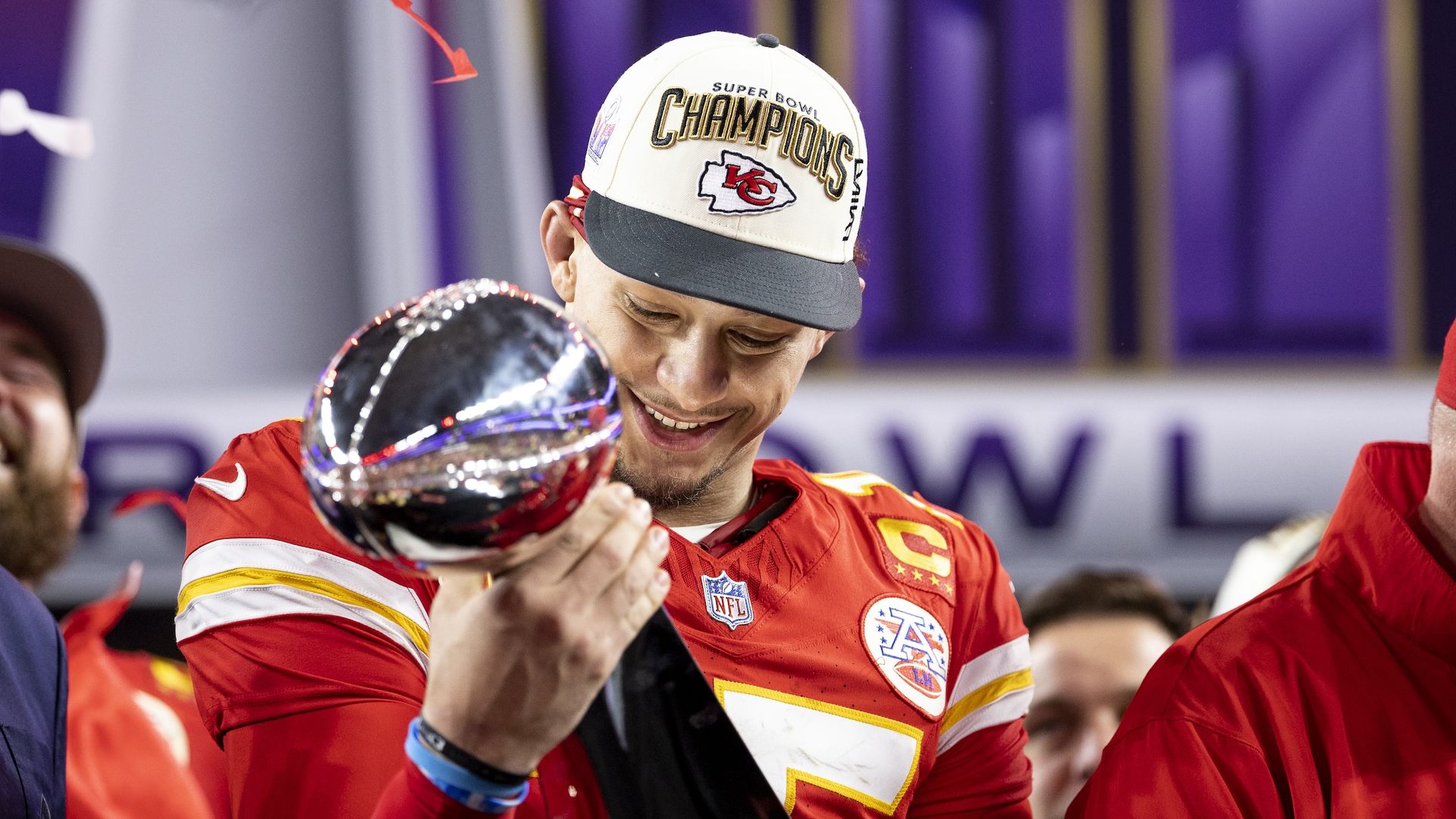 Patrick Mahomes of the Kansas City Chiefs holds and looks at the Vince Lombardi Trophy.