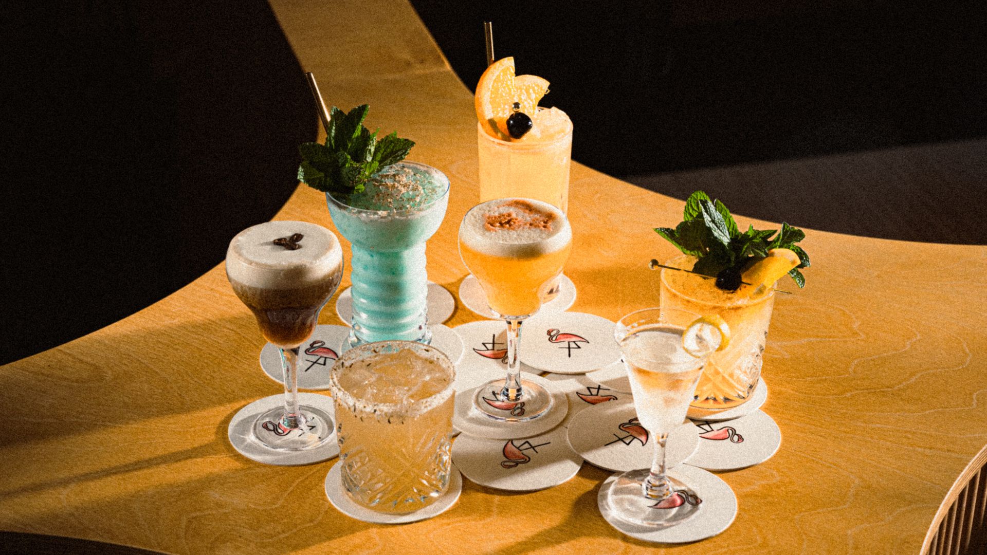 A photo of seven cocktails on a square table.