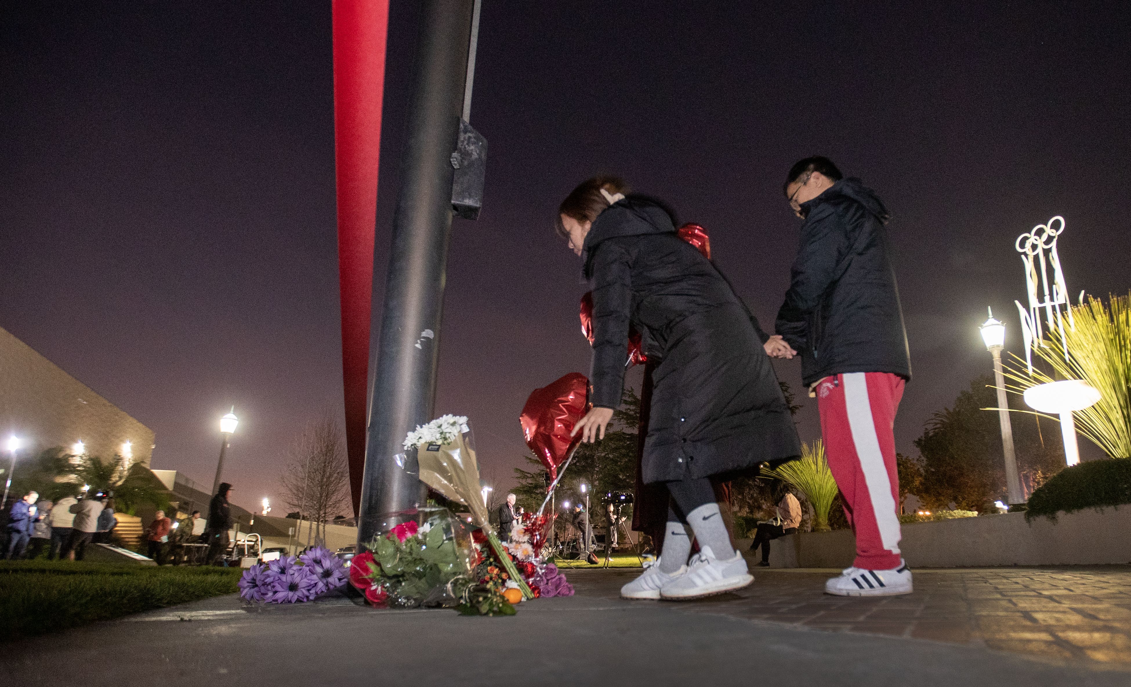 People who brought flowers join another paying their respects at a memorial for Monterey Park mass shooting victims after a news conference at the Monterey Park Civic Center on Sunday, Jan. 22. 