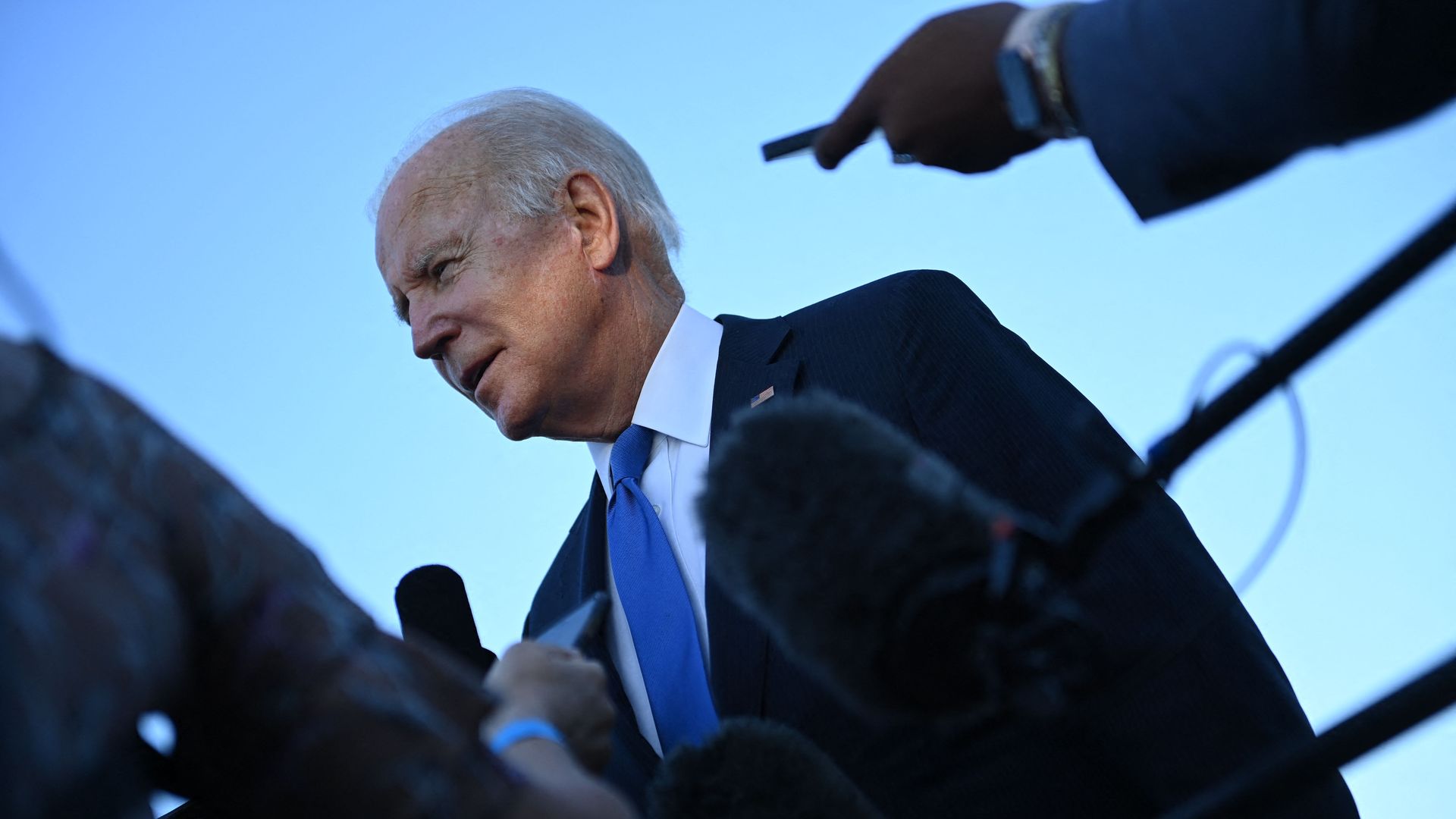 Photo of Joe Biden standing next to reporters who are holding out their phones at him
