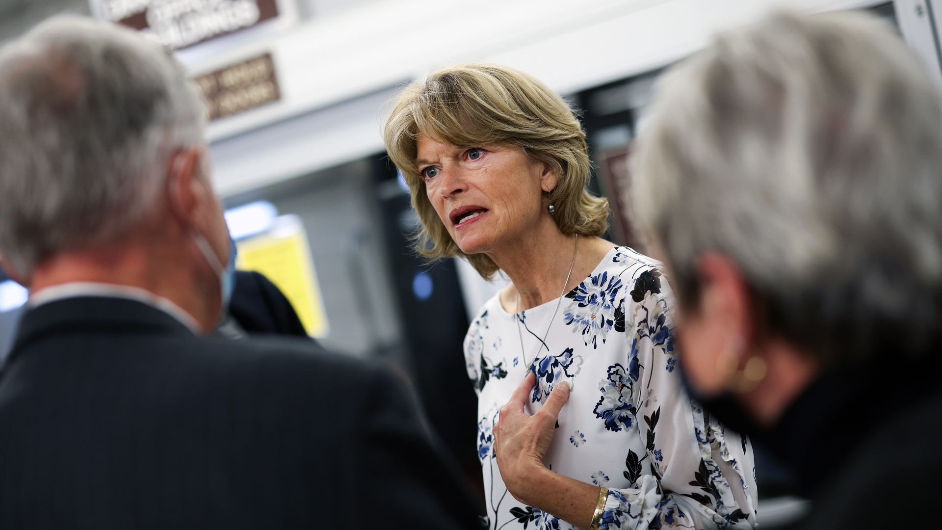 Photo of Lisa Murkowski speaking to reporters with one hand over her heart