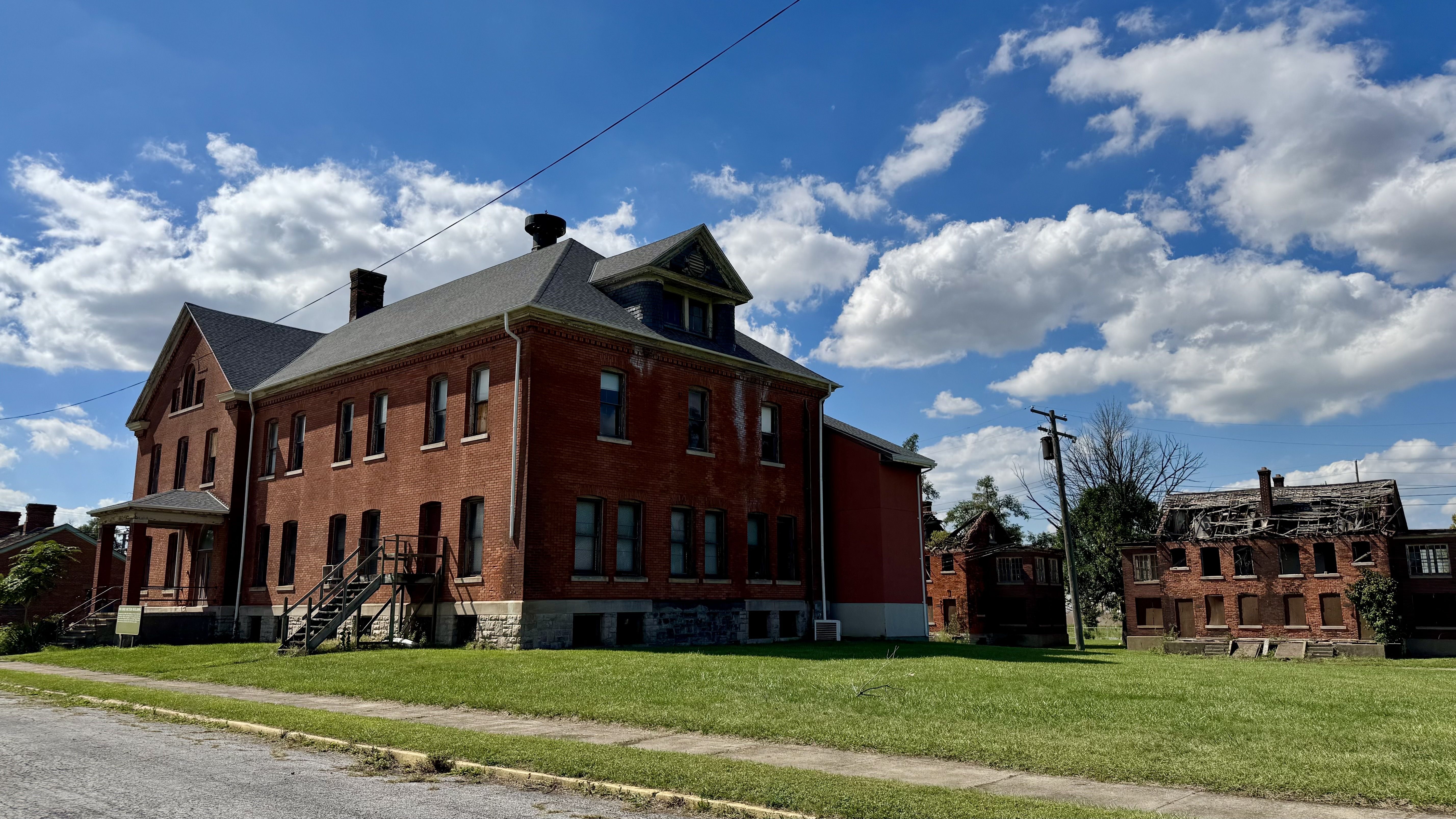 A brick building with an intact roof next to a building with a caving-in roof