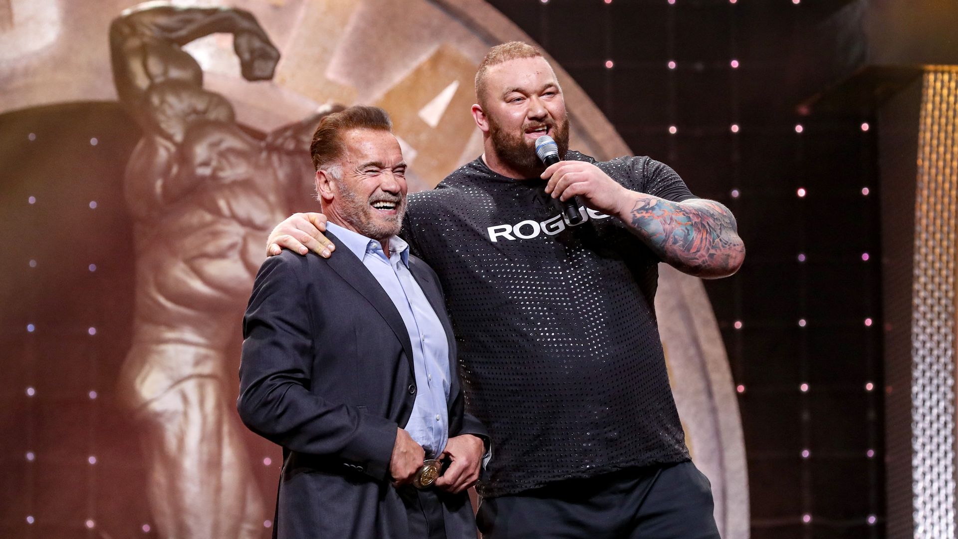Arnold Schwarzenegger and bodybuilder Hafthor Bjornsson stand on stage together.