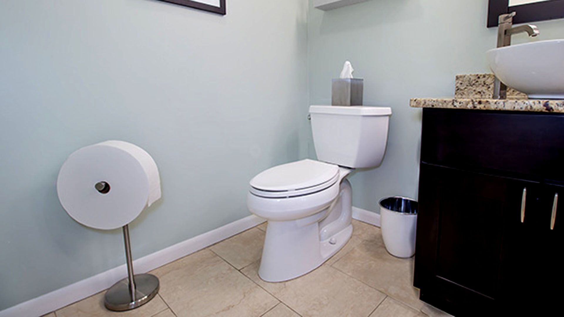 A huge roll of toilet paper next to a sink and toilet
