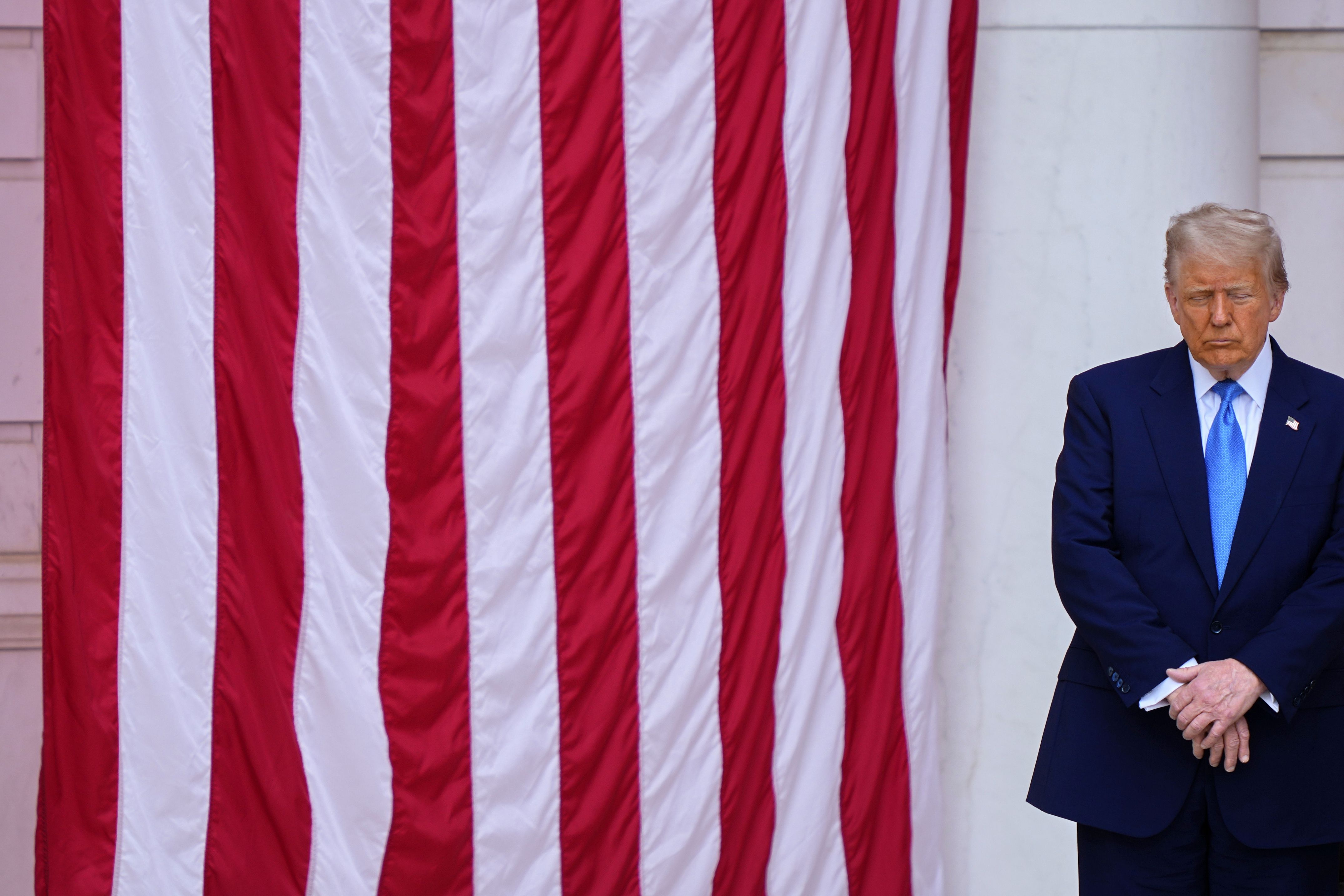 President Trump bows his head in prayer with others before delivering a  Memorial Day address at Arlington National Cemetery  yesterday.