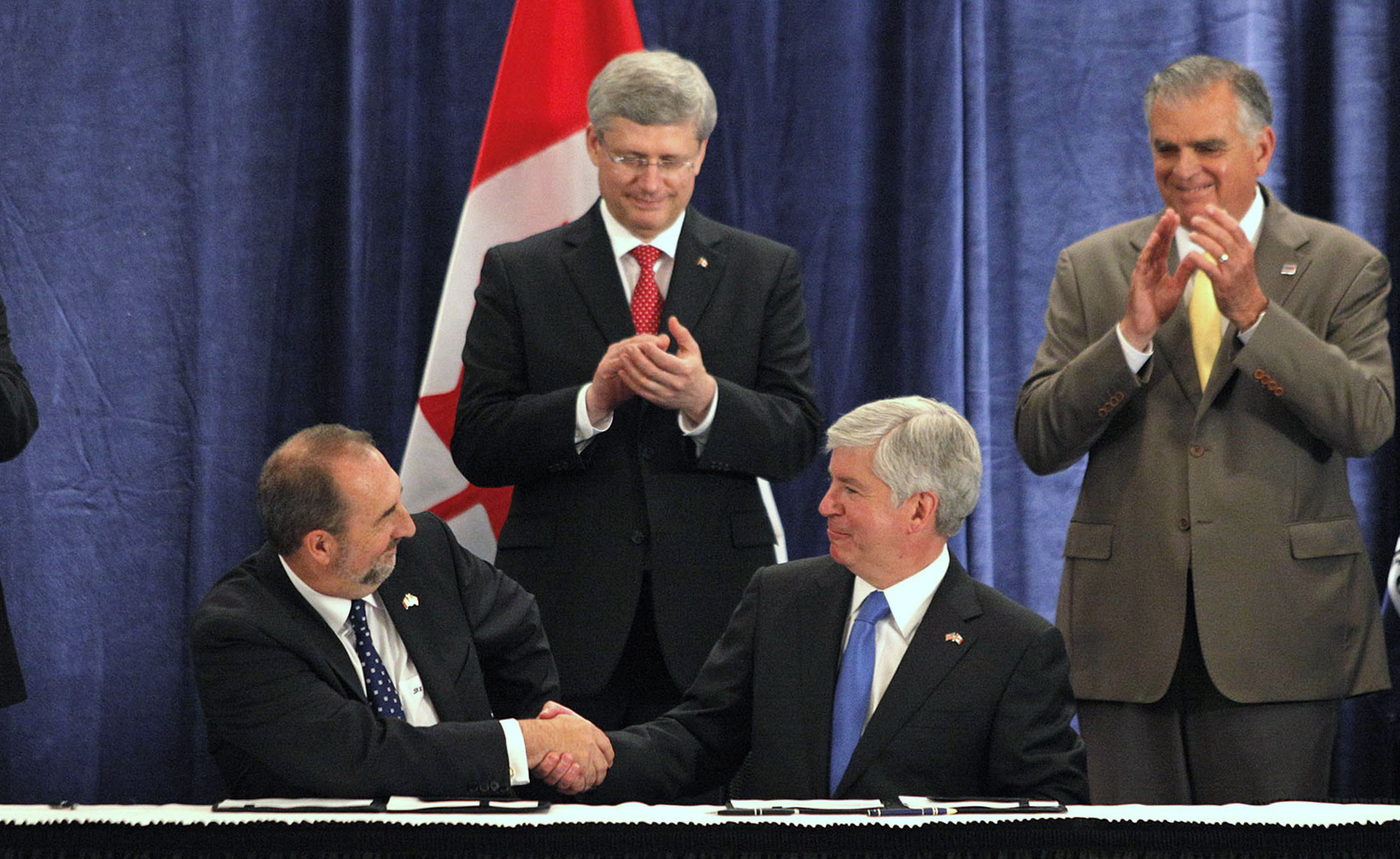 Snyder shakes hands with a Canadian official while others clap