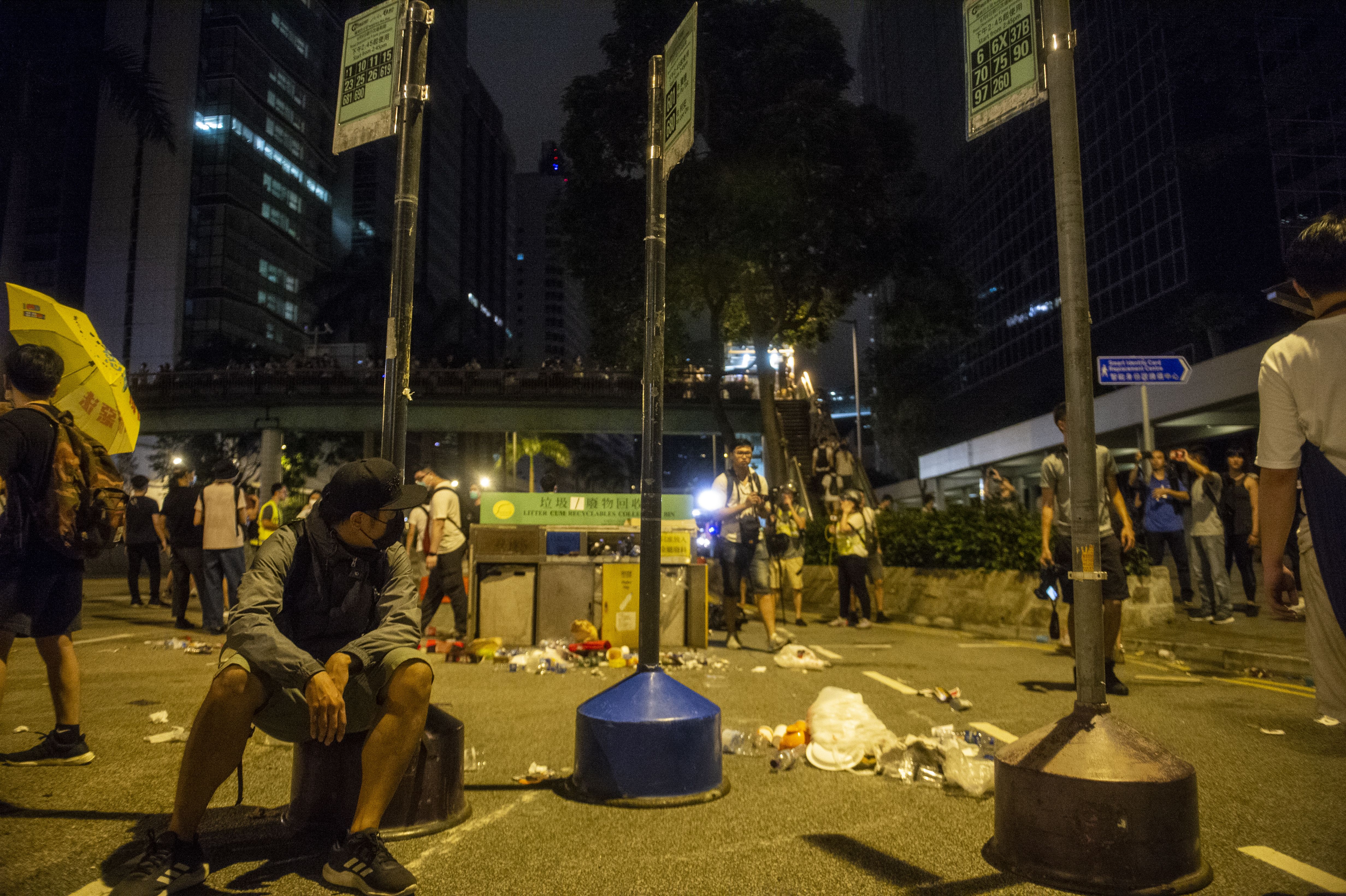 A protester is seen sitting next to bus stand put on the road as barricades in Hong Kong, China. 