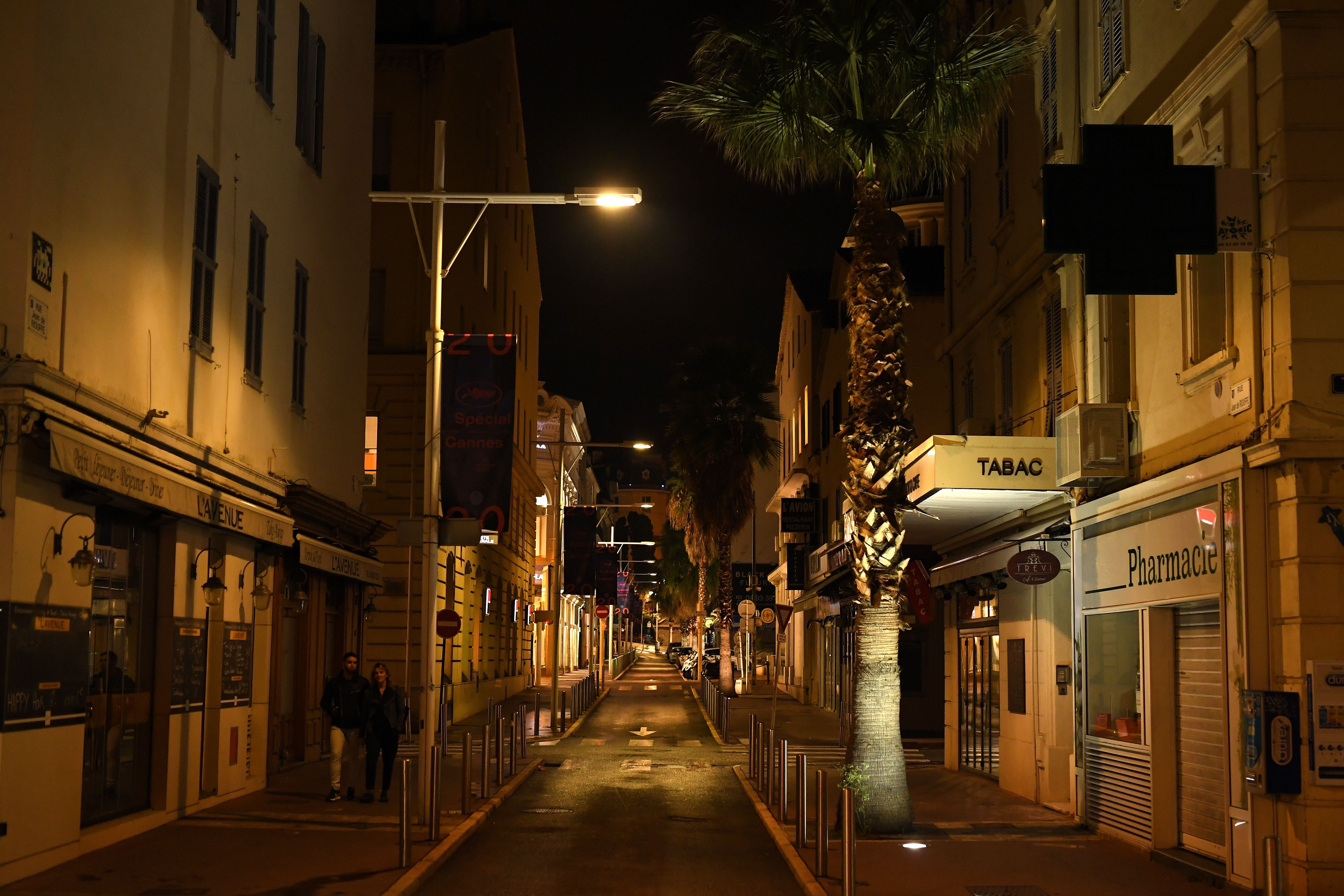 Pedestrians walk along an empty street on Oct. 25 in Cannes, on the French Riviera