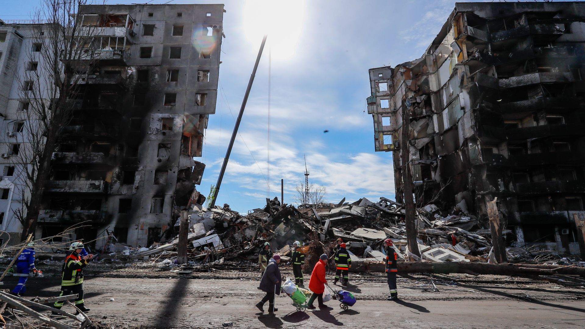 People sift through collapsed buildings and debris in a suburb of Kyiv