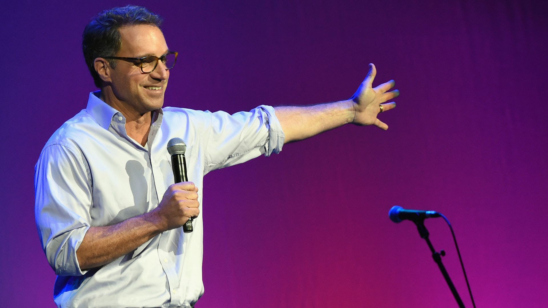 Hal Cato stands on stage with a microphone.